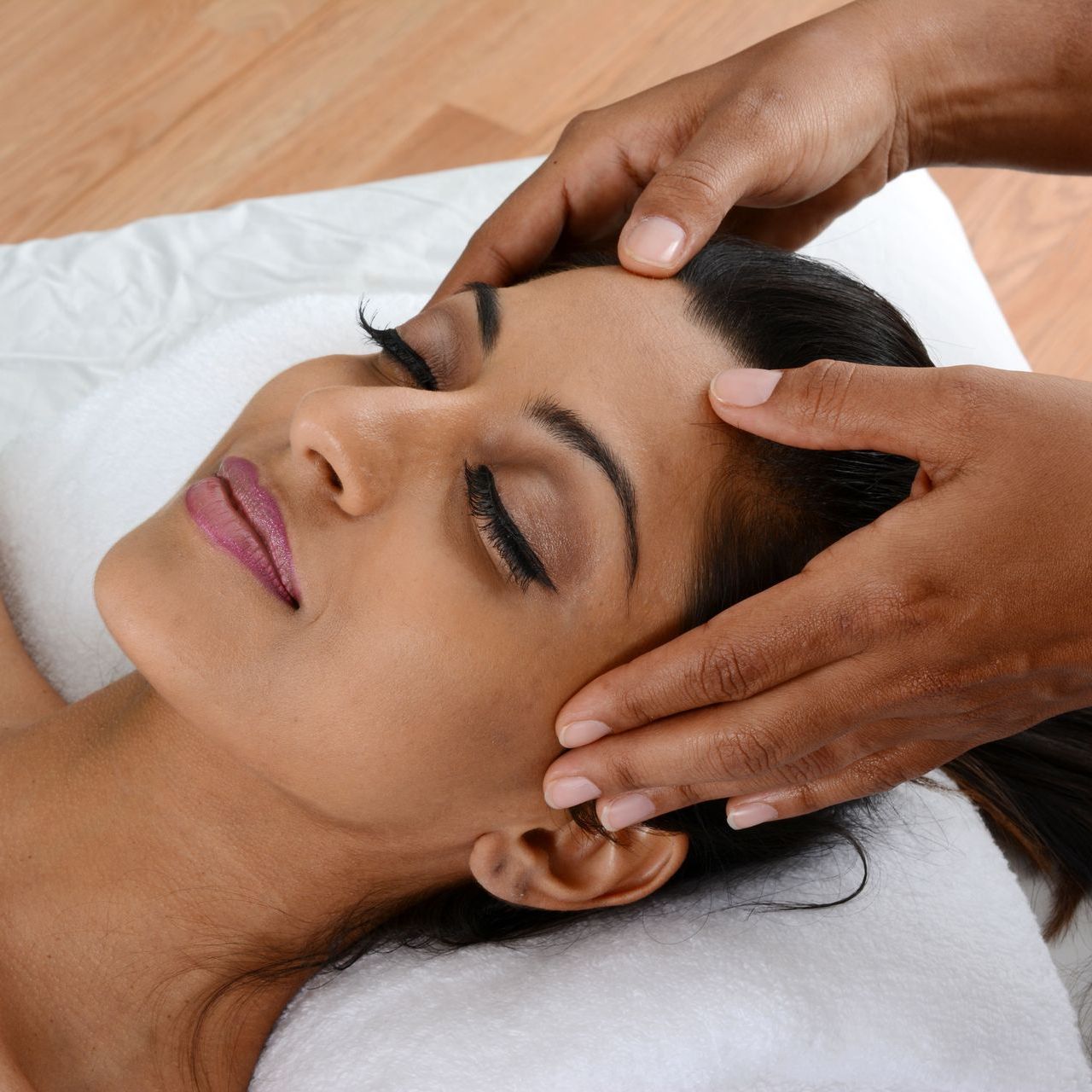 A woman is getting a head massage with her eyes closed