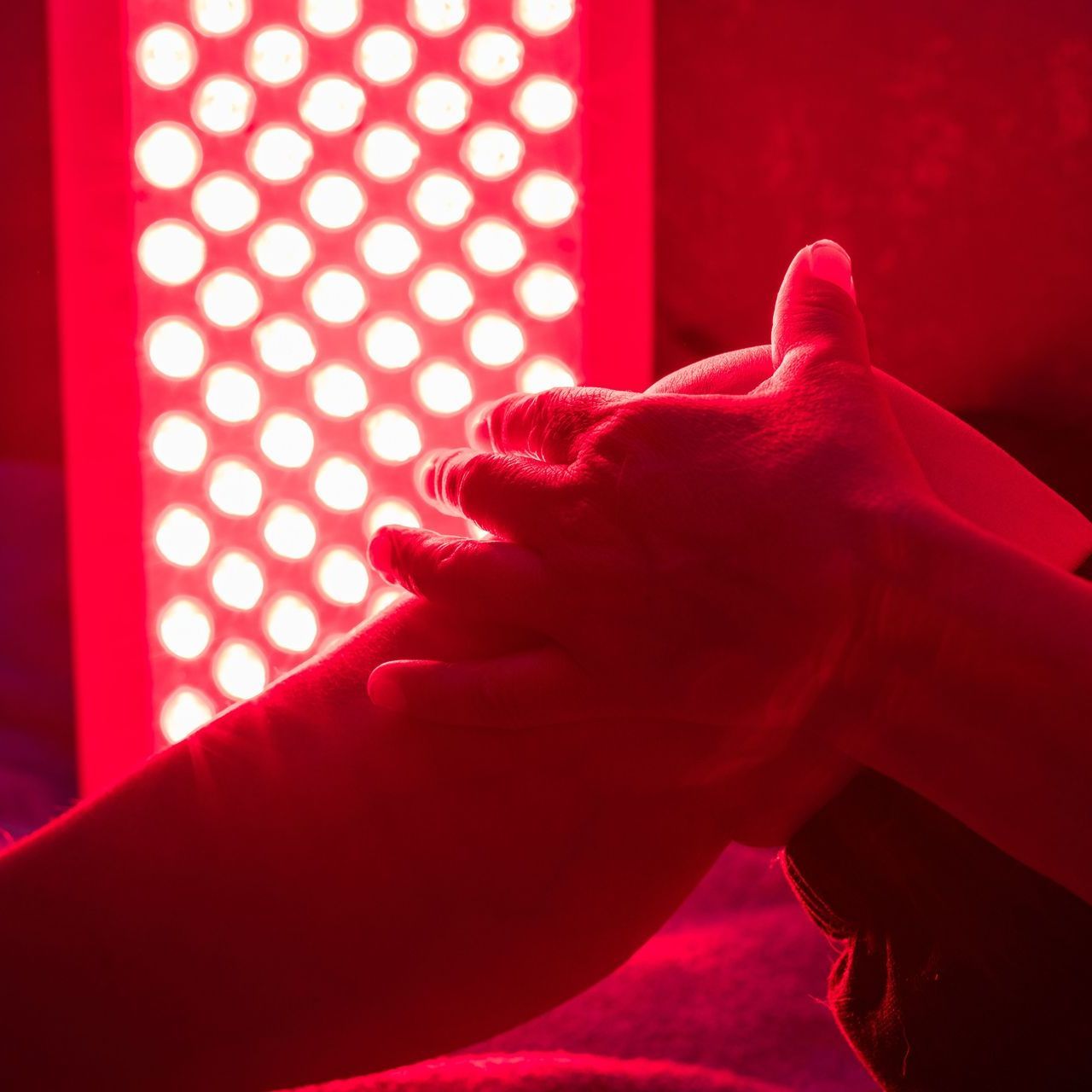 A person is holding his knee in front of a red light.