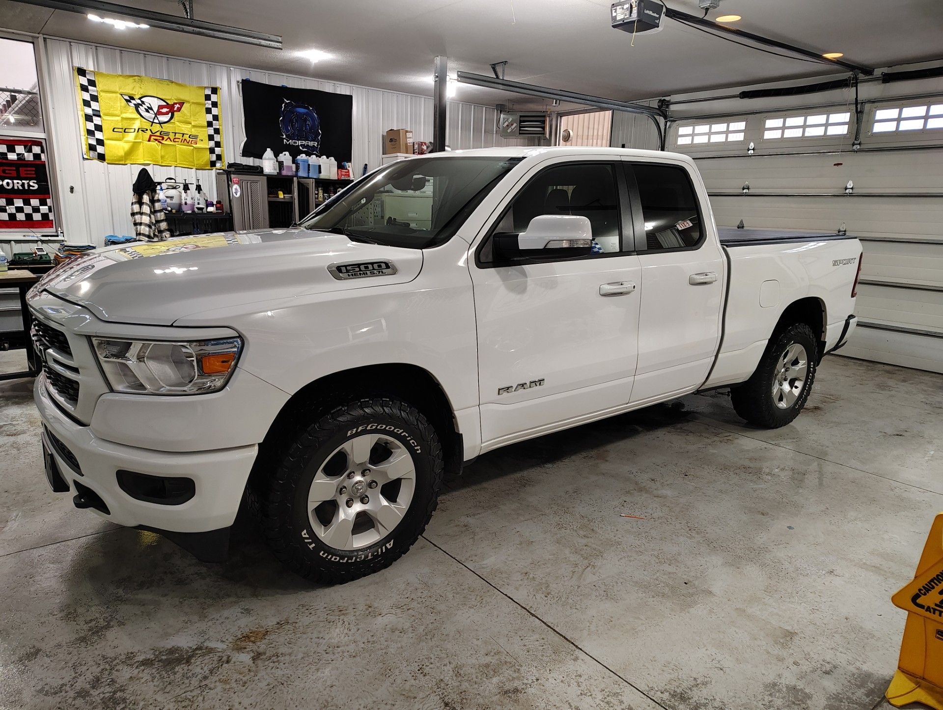 A white Ram pickup truck parked in a well-lit garage, positioned at a slight angle on a concrete floor.