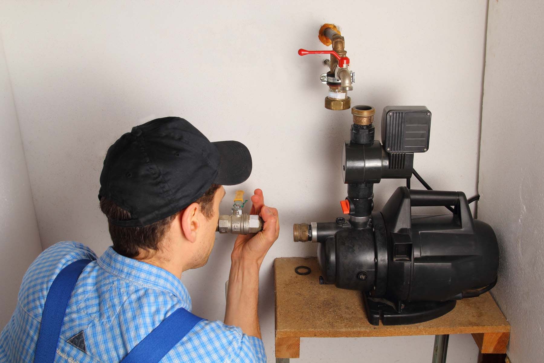 A man is working on a water pump in a room.