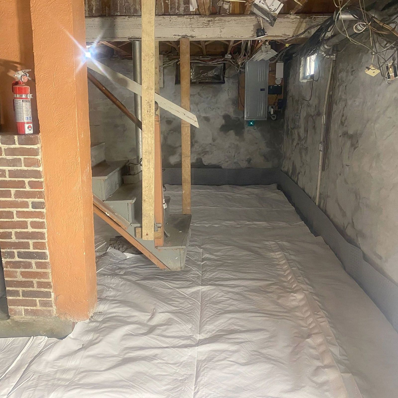 Basement with insulation on the floor, stairs, brick chimney, and water heater visible