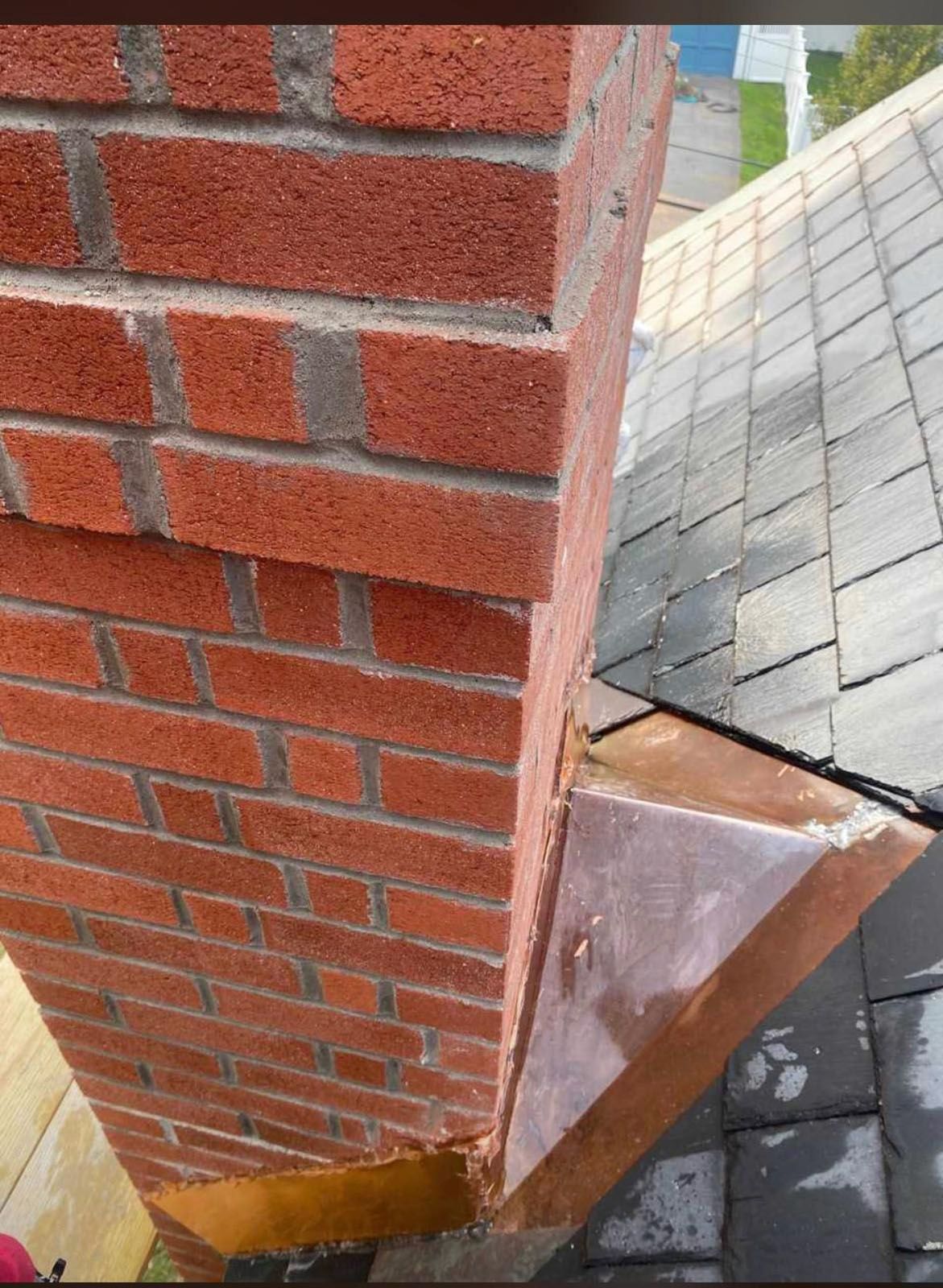 Red brick chimney next to a gray shingle roof
