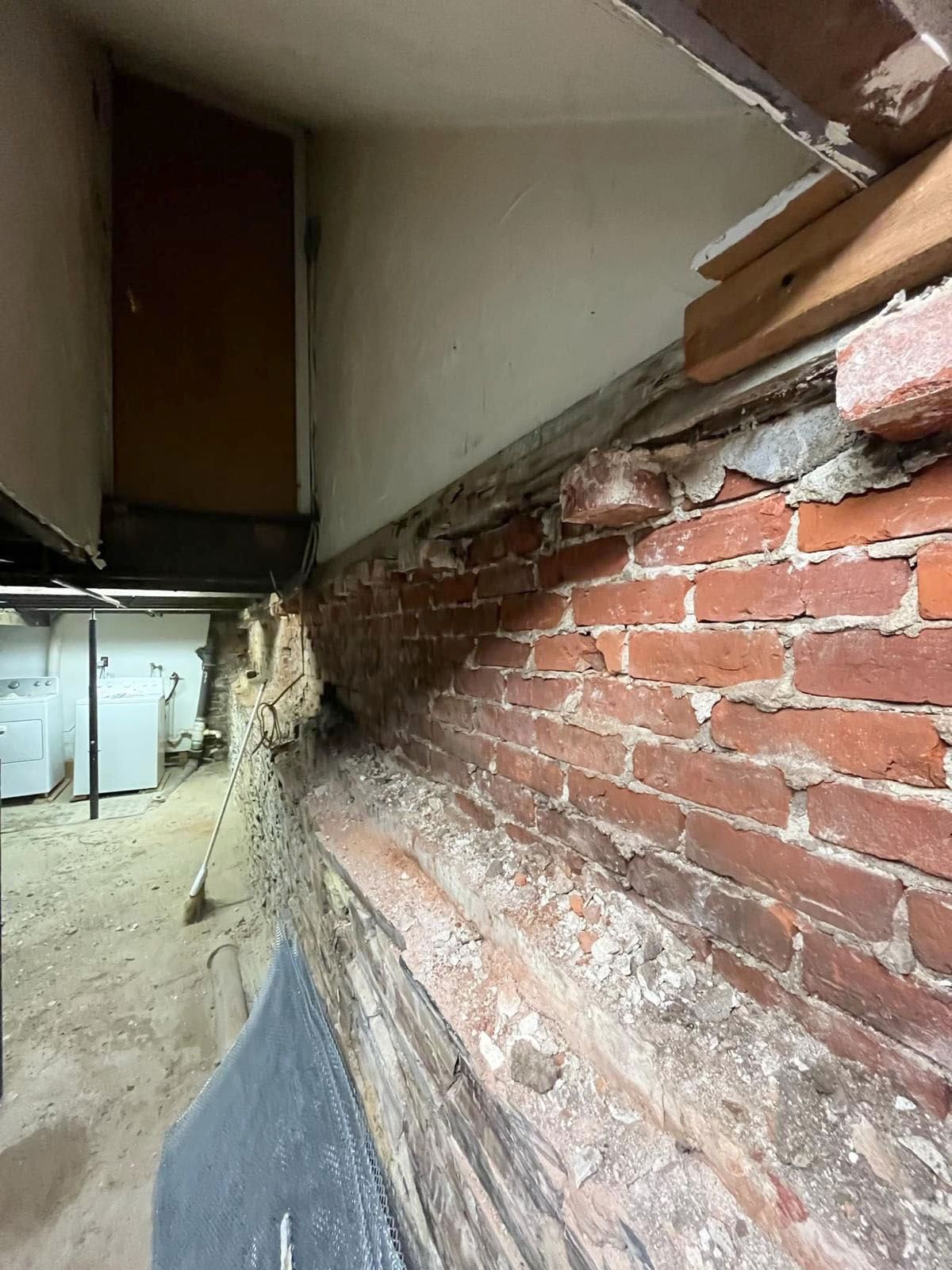 Brick wall with deteriorated mortar and wood, basement setting.
