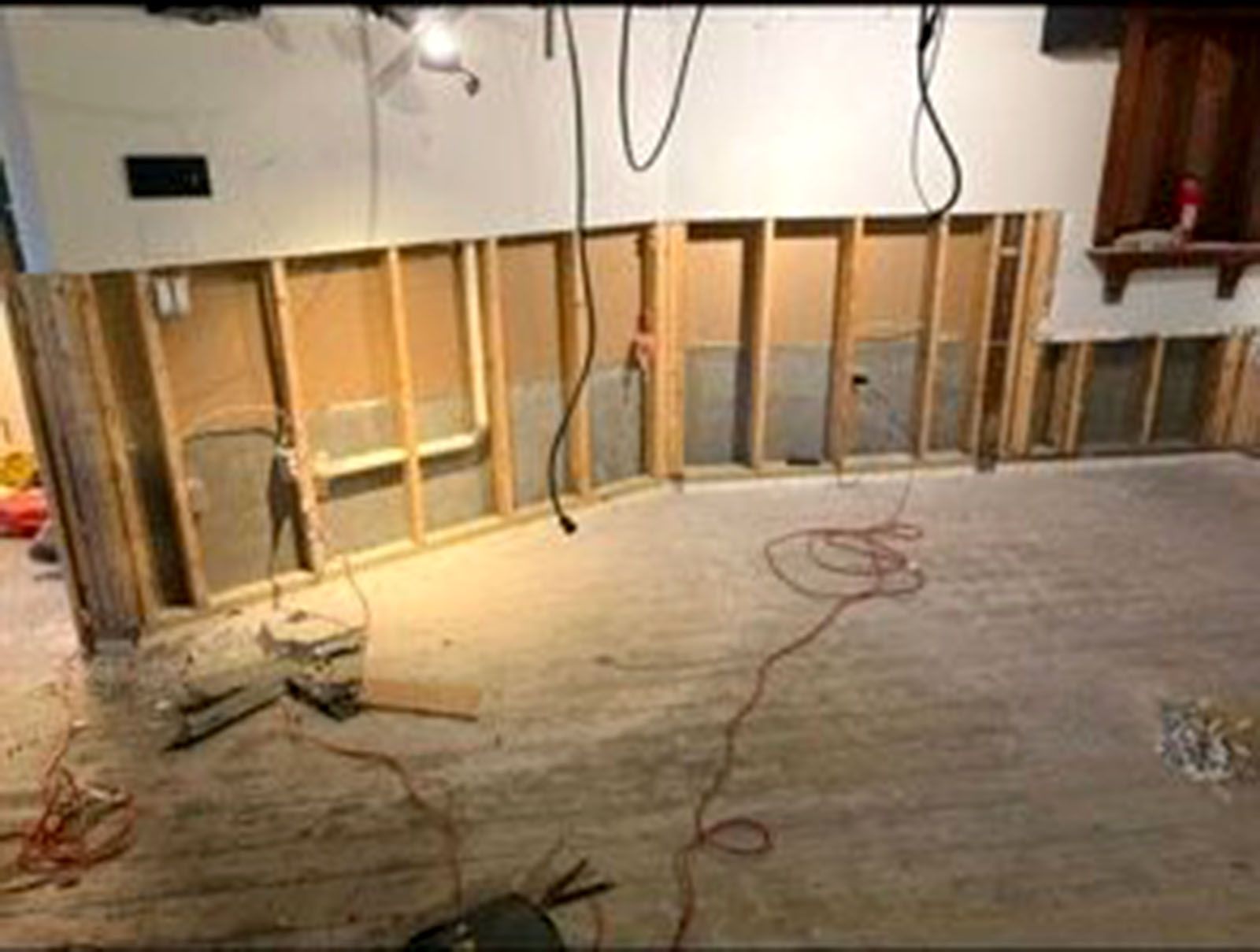 Basement wall under construction: exposed studs, electrical wires, and concrete floor.