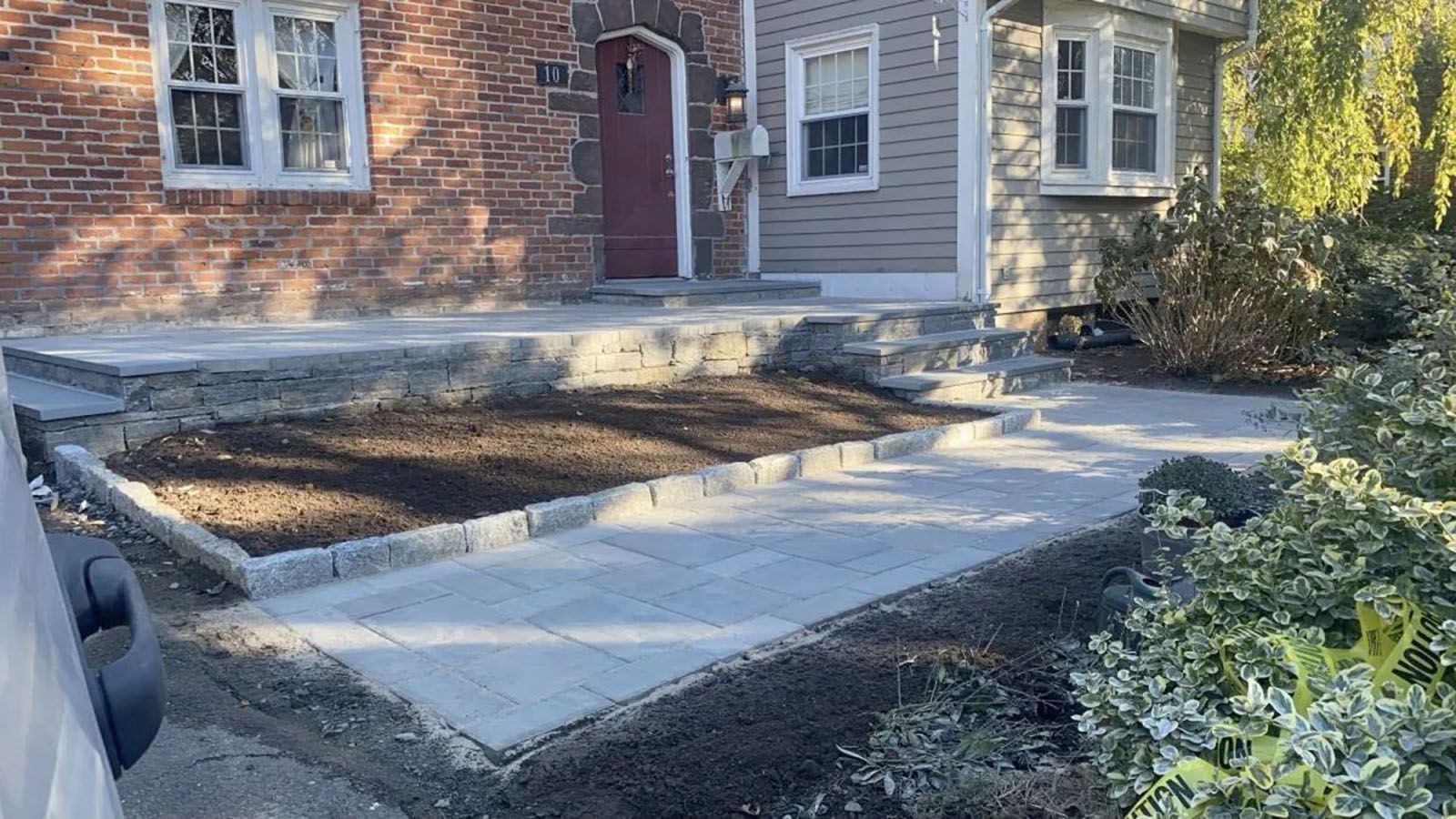 Newly constructed concrete walkway and steps leading to a house with brick and siding.