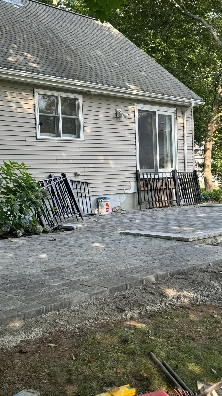 Backyard with a small house, patio pavers, and building materials.