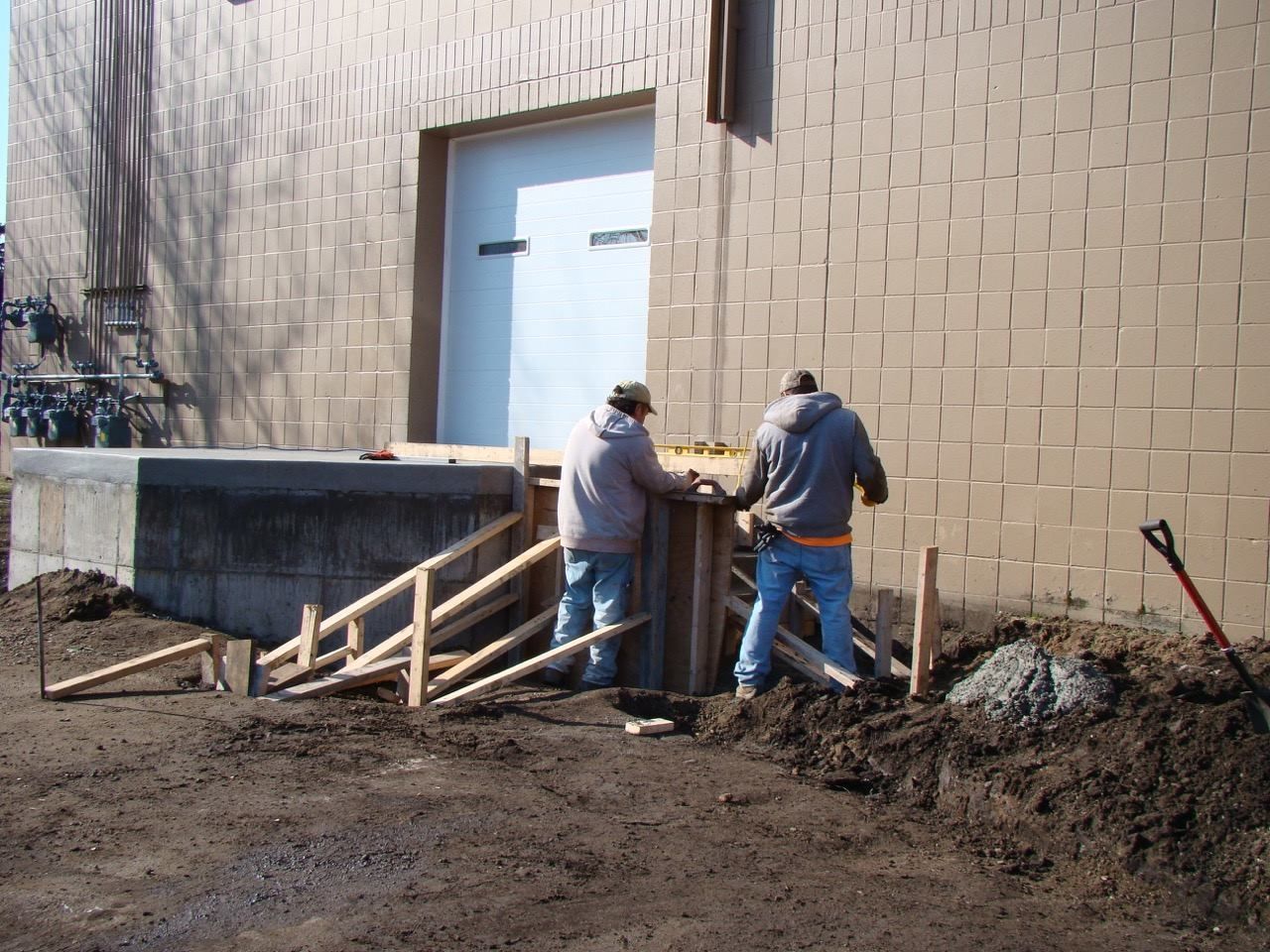 Two men are standing in front of a brick building