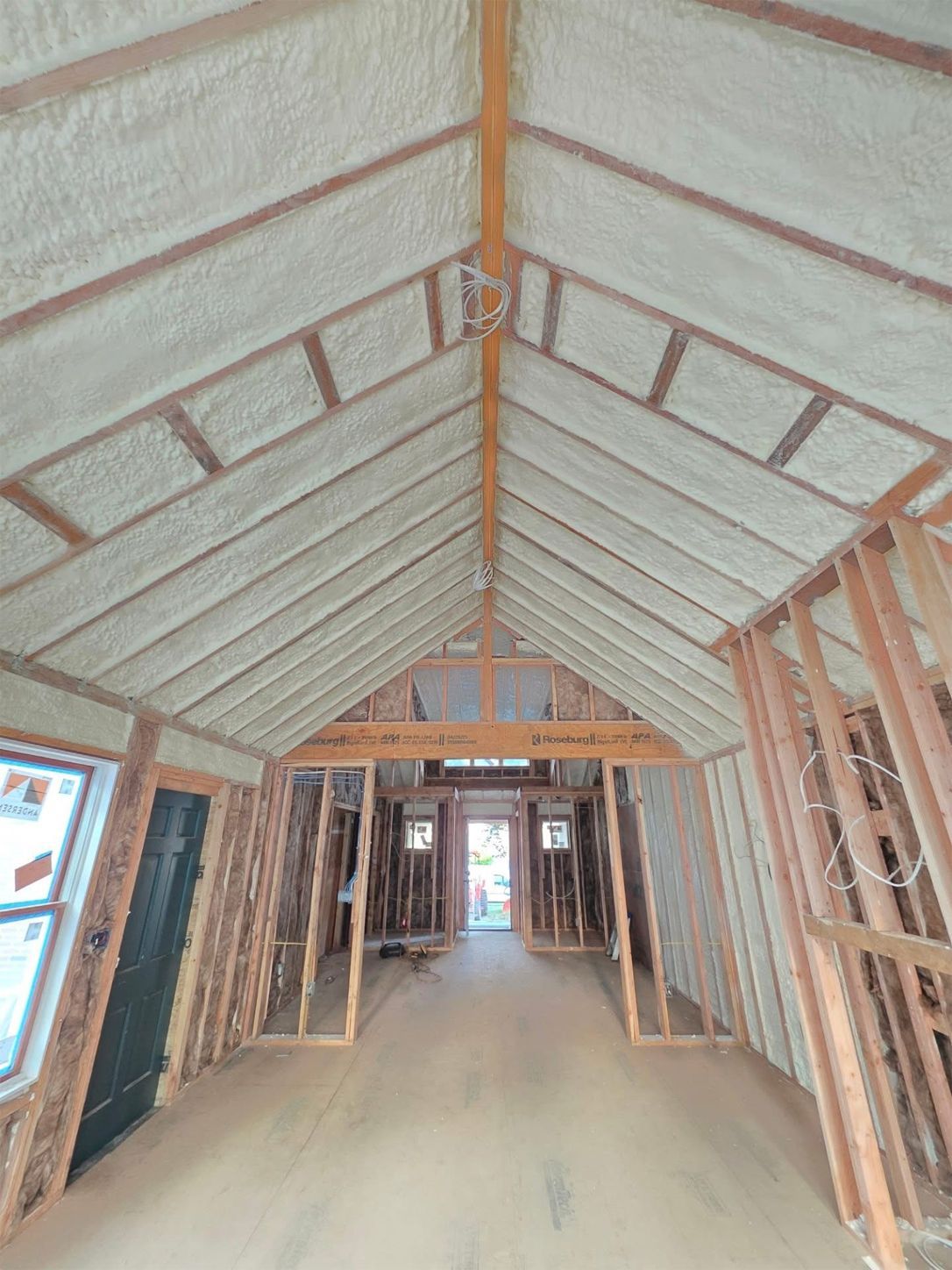 Interior view of a new construction with spray foam insulation on the roof and exposed wood framing.