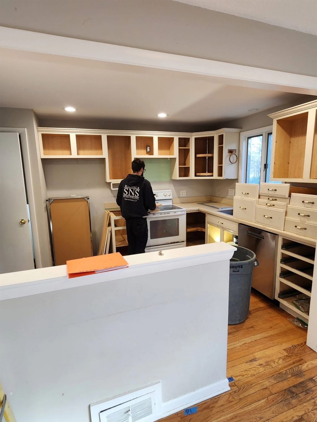 A person installing kitchen cabinets in a room with light-colored walls.