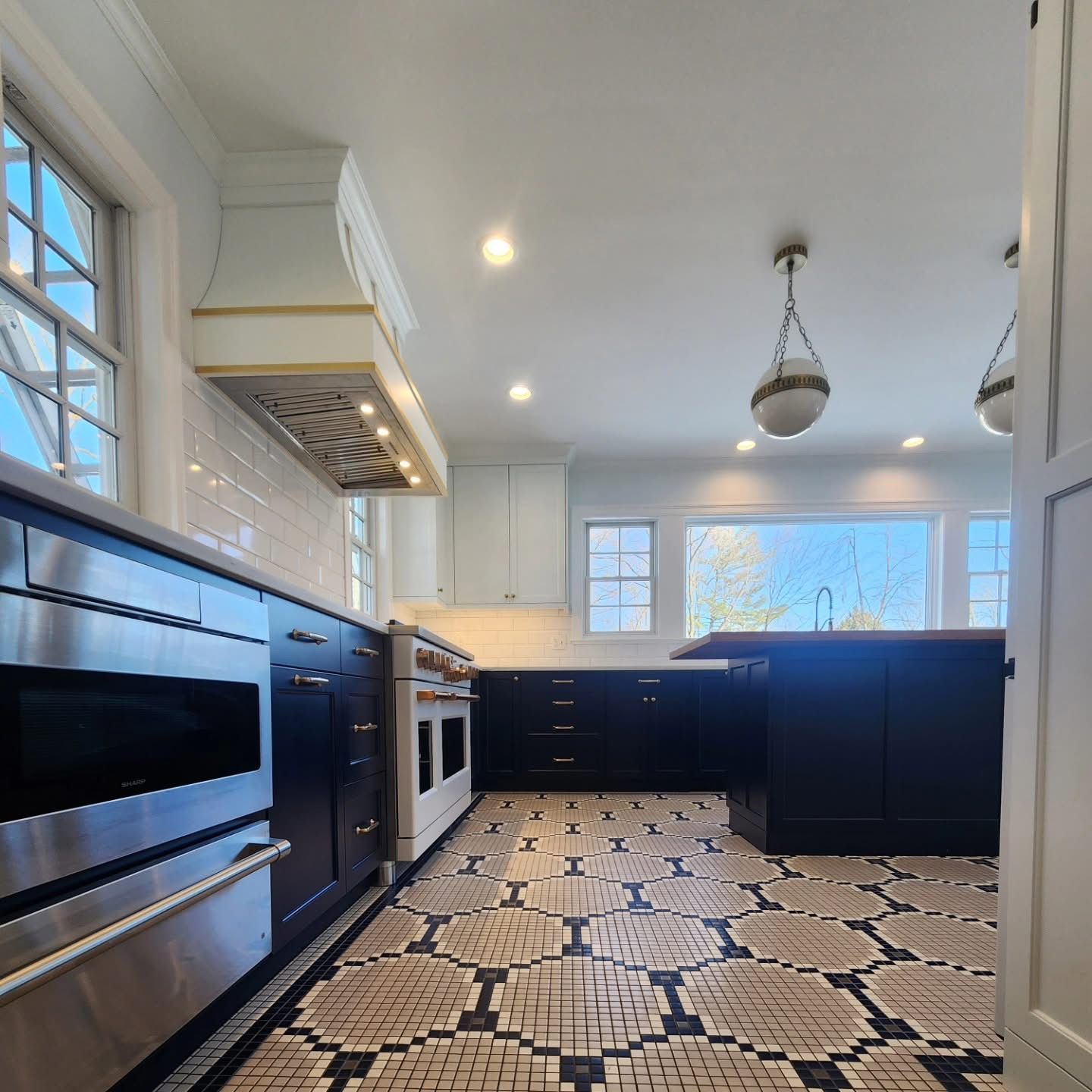 Modern kitchen with black cabinets, patterned floor, and stainless steel appliances.