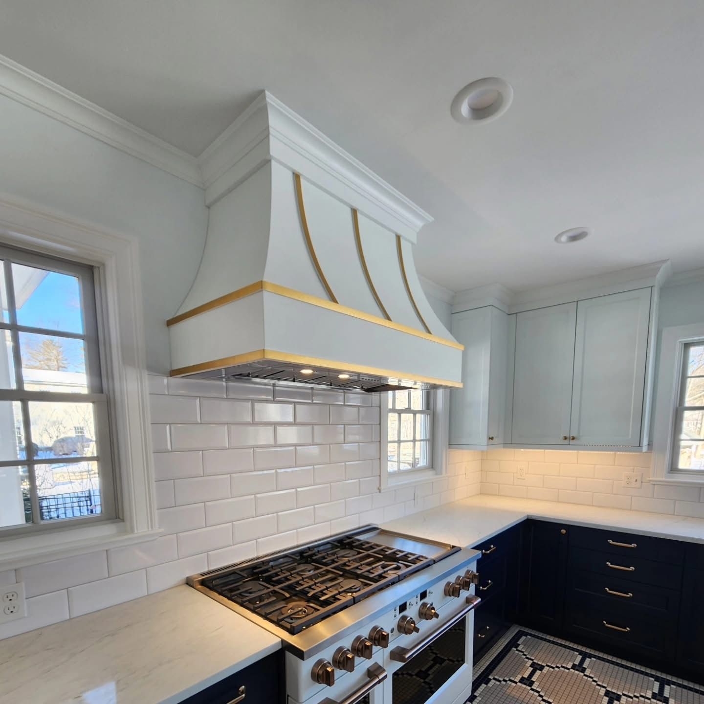 White kitchen with a gas range, blue cabinets, and a decorative hood.