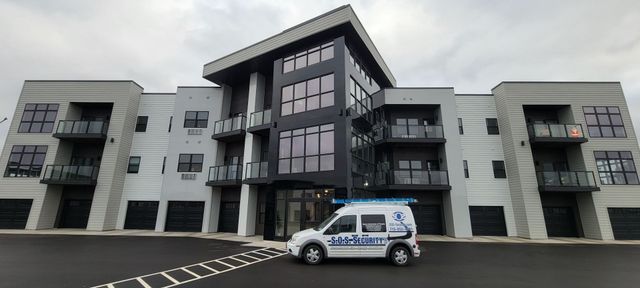 Modern apartment building with a white van parked in front. Cloudy sky.