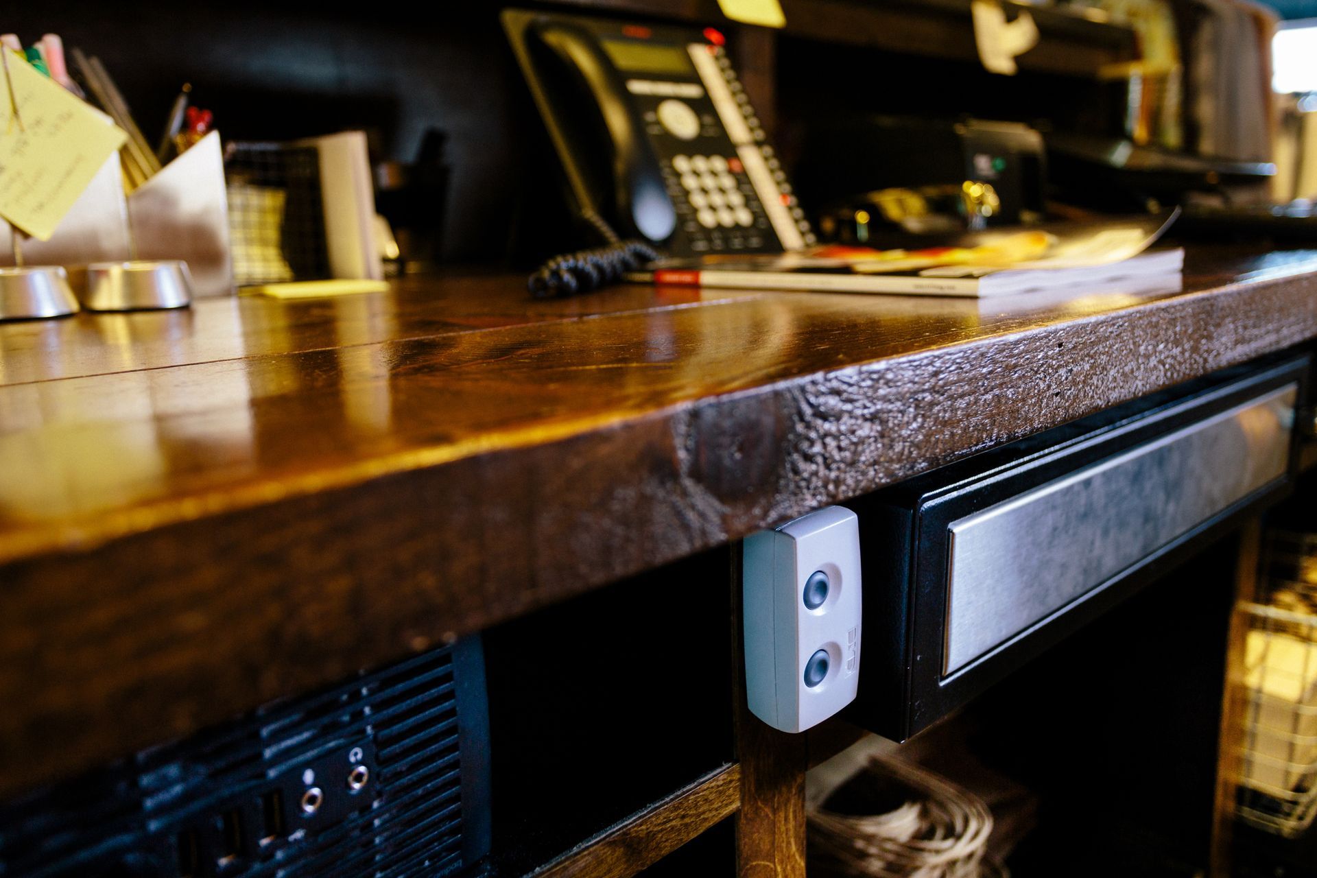 Close-up of a wooden bar with an electrical outlet and a cooler visible underneath.