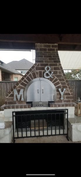 Outdoor brick pizza oven with a stainless steel arched door, decorated with large metal 