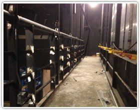 An interior catwalk in a theater, showing metal railings and lighting equipment along a concrete walkway.