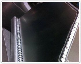 Close-up of two distinct, high-quality aluminum TIG welds joining metal plates at a right angle.