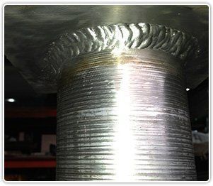 A close-up view of a metal cylinder welded to a flat metal plate, showing a circular, textured weld bead at the joint.