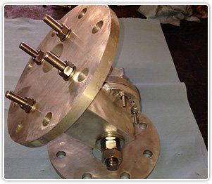 Two bronze-colored circular industrial flanges connected by a short, angled central housing with threaded bolts and nuts.