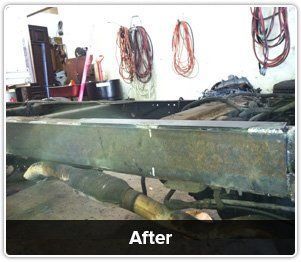 A vehicle chassis frame in a workshop, showing repaired metalwork with welding marks, labeled 