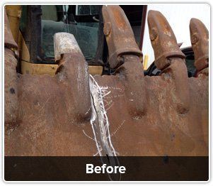 A close-up of a rusted excavator bucket showing a large, marked metal crack between the teeth labeled 