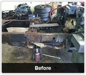 A rusted truck chassis being repaired with a hydraulic jack in an automotive shop, labeled 