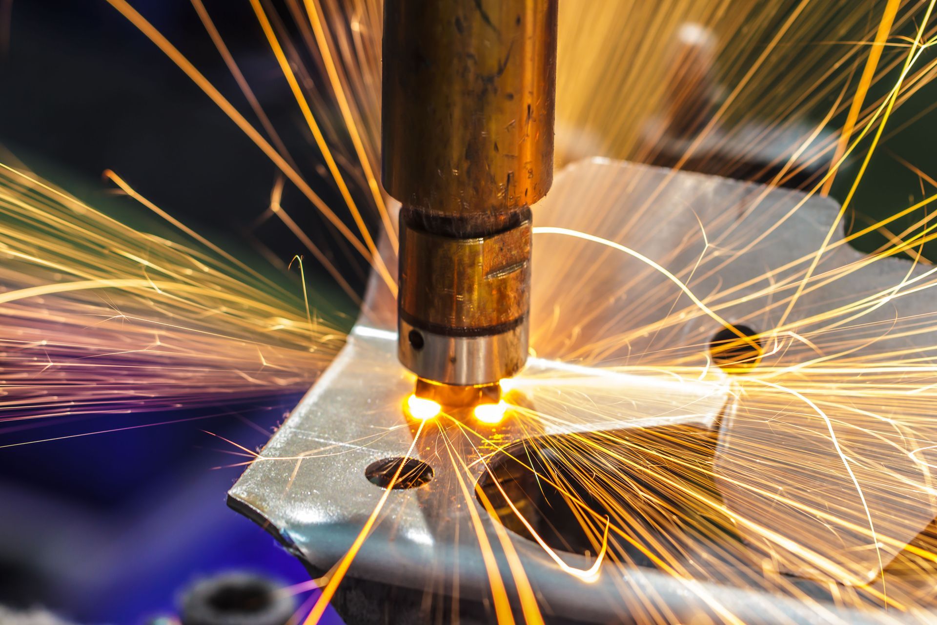 Close-up of industrial spot welding on a metal sheet, creating a bright glow and flying orange sparks.