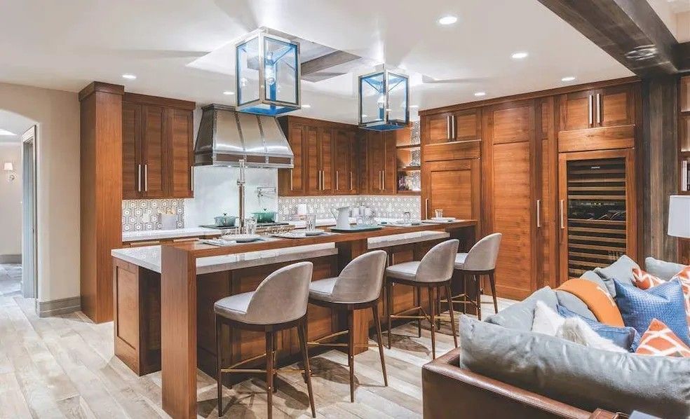 Wooden kitchen with island, stools, cabinets, stainless hood, and blue lantern lights.