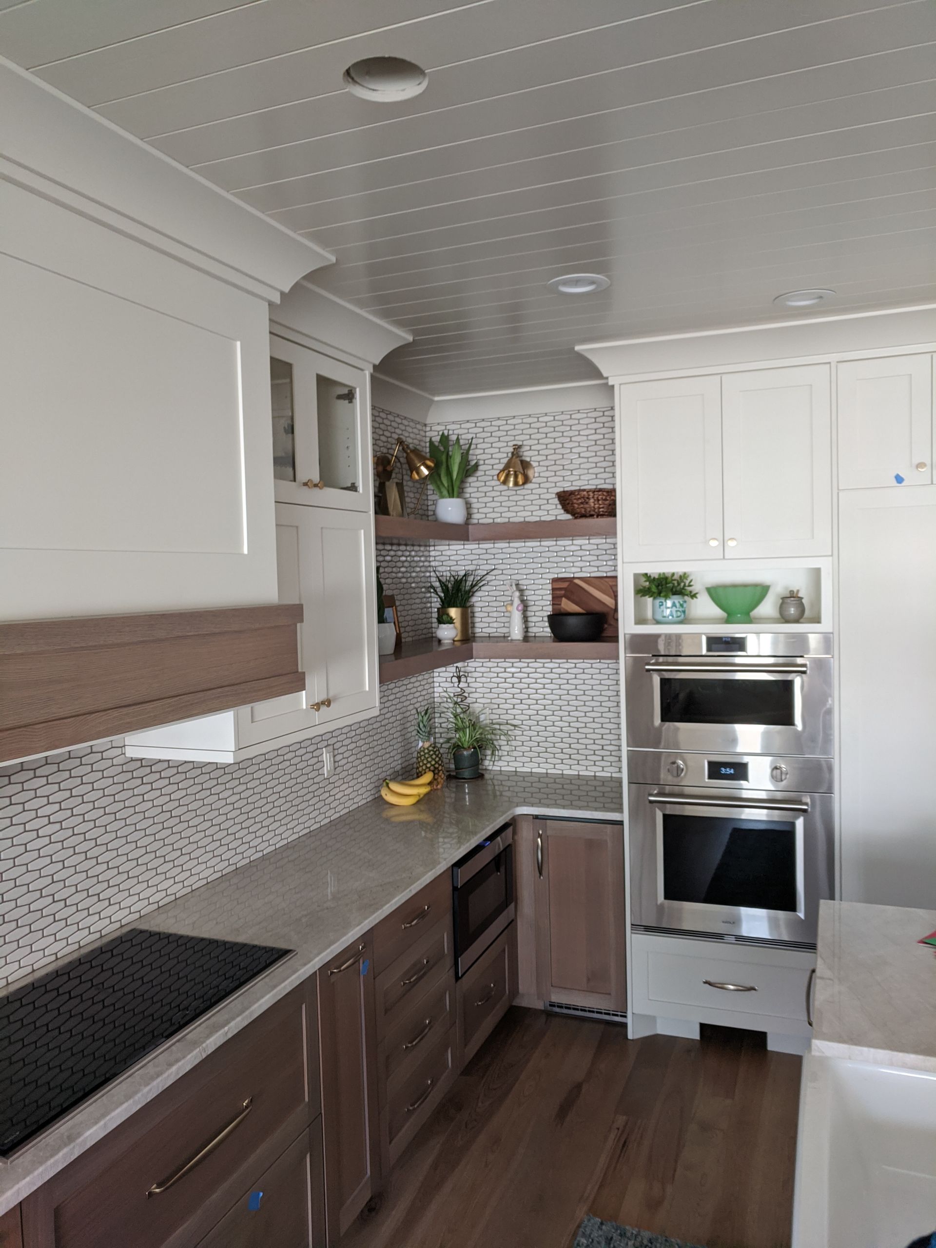 Kitchen with white cabinets, stainless steel appliances, and wood accents; light tile backsplash.