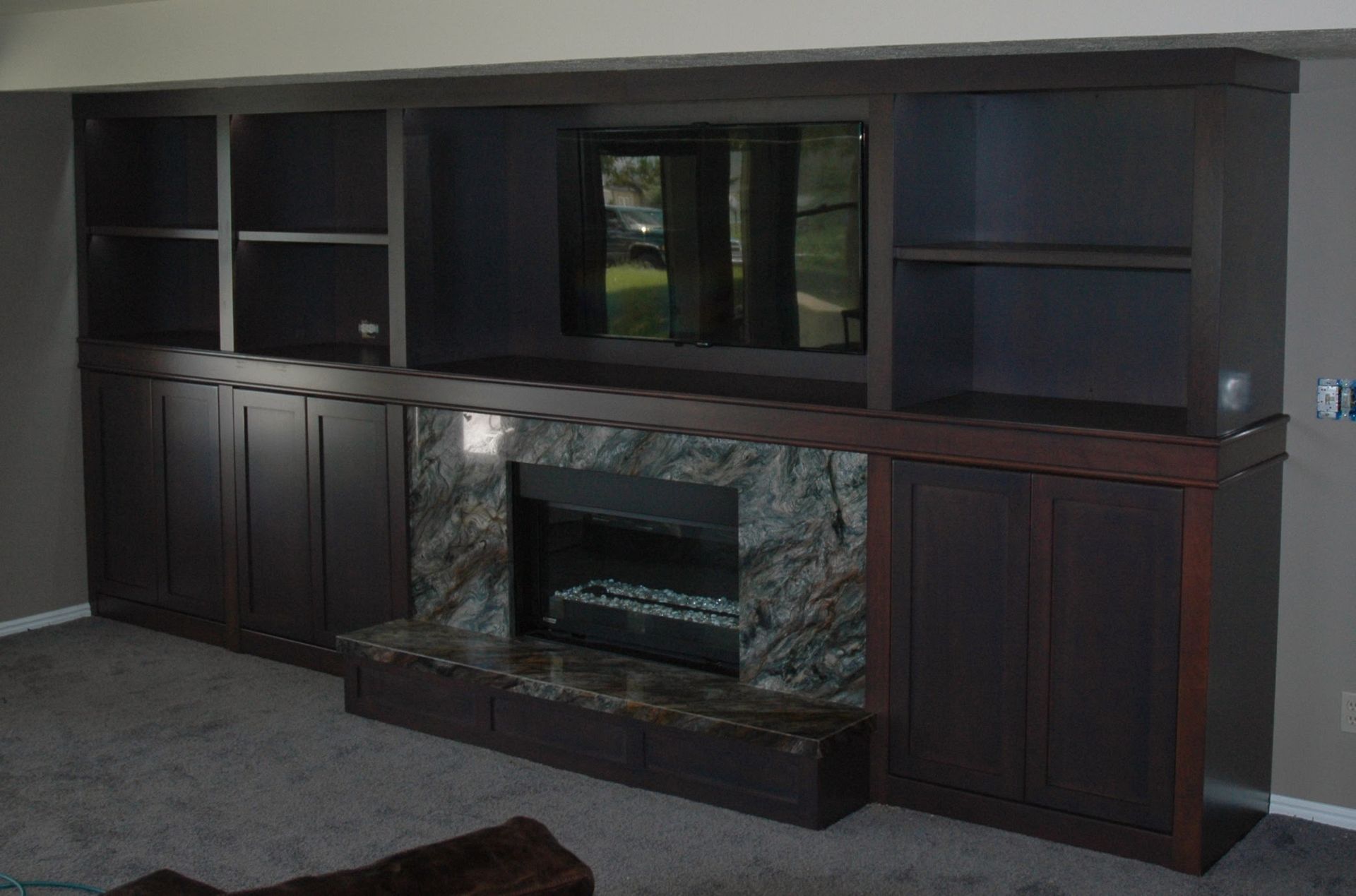 Built-in dark wood entertainment center with fireplace and TV.