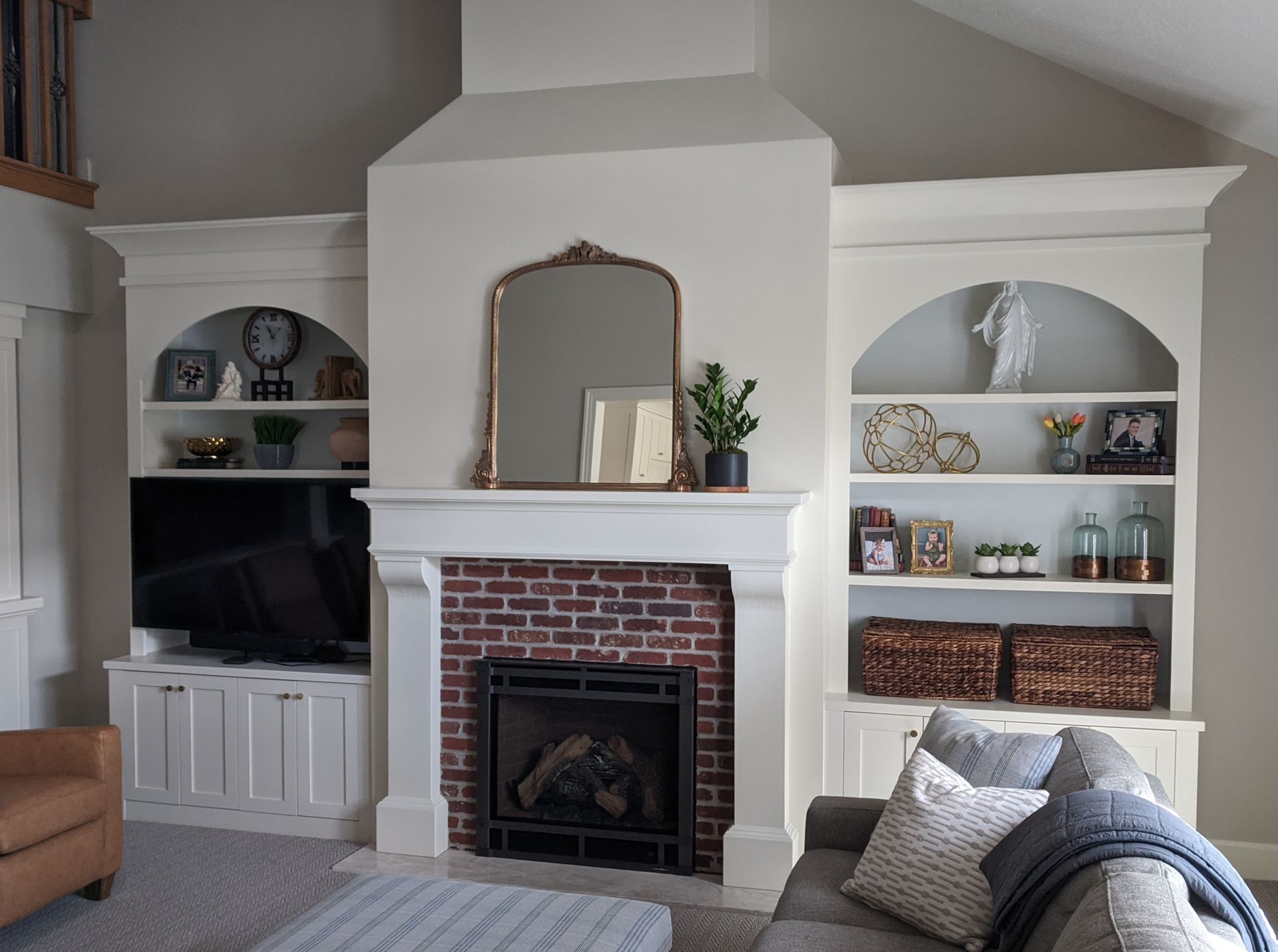 Living room with fireplace, built-in bookshelves, and couch. White and brick accents.