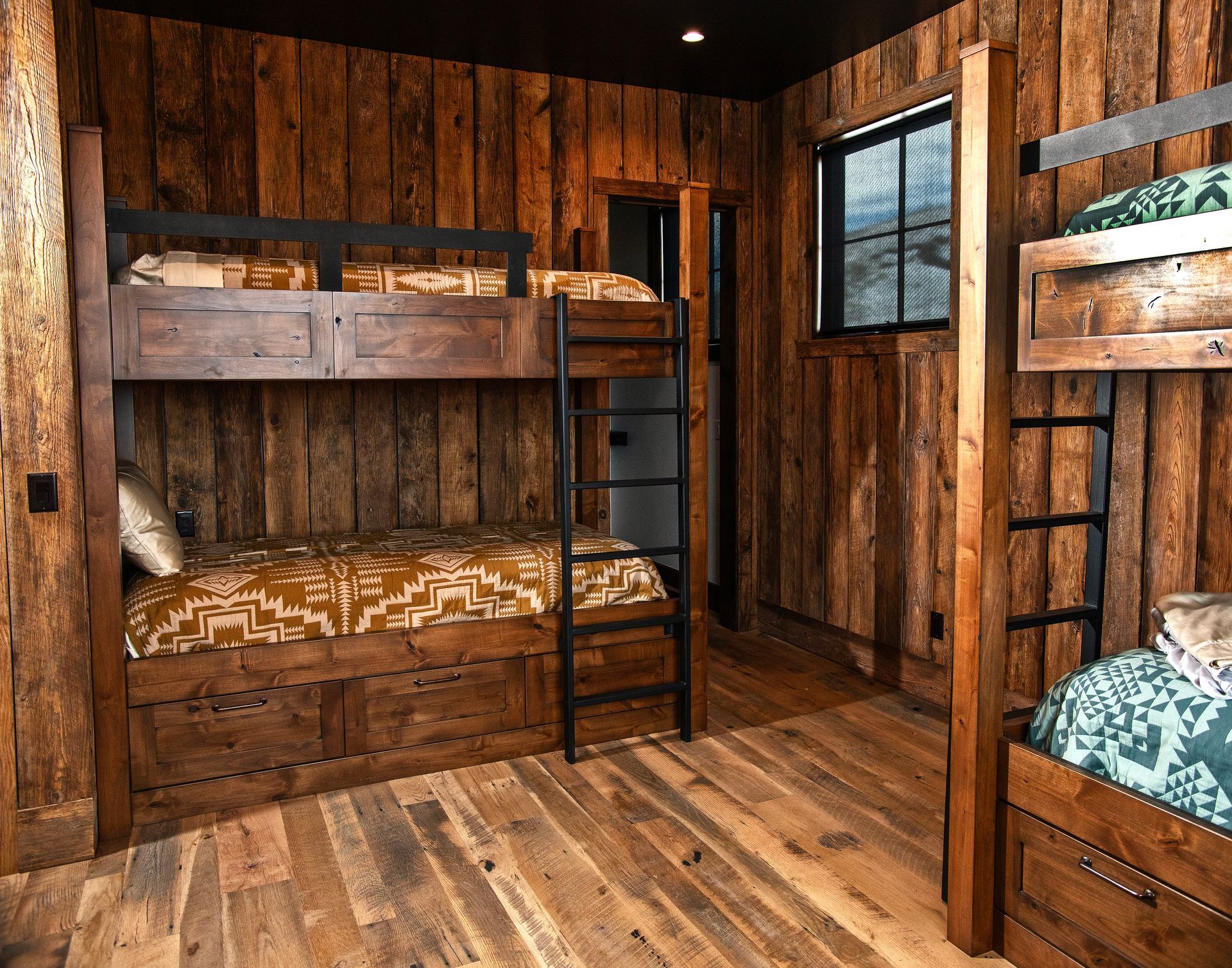 Rustic bunk beds in a cabin-style bedroom, featuring wood paneling and flooring.