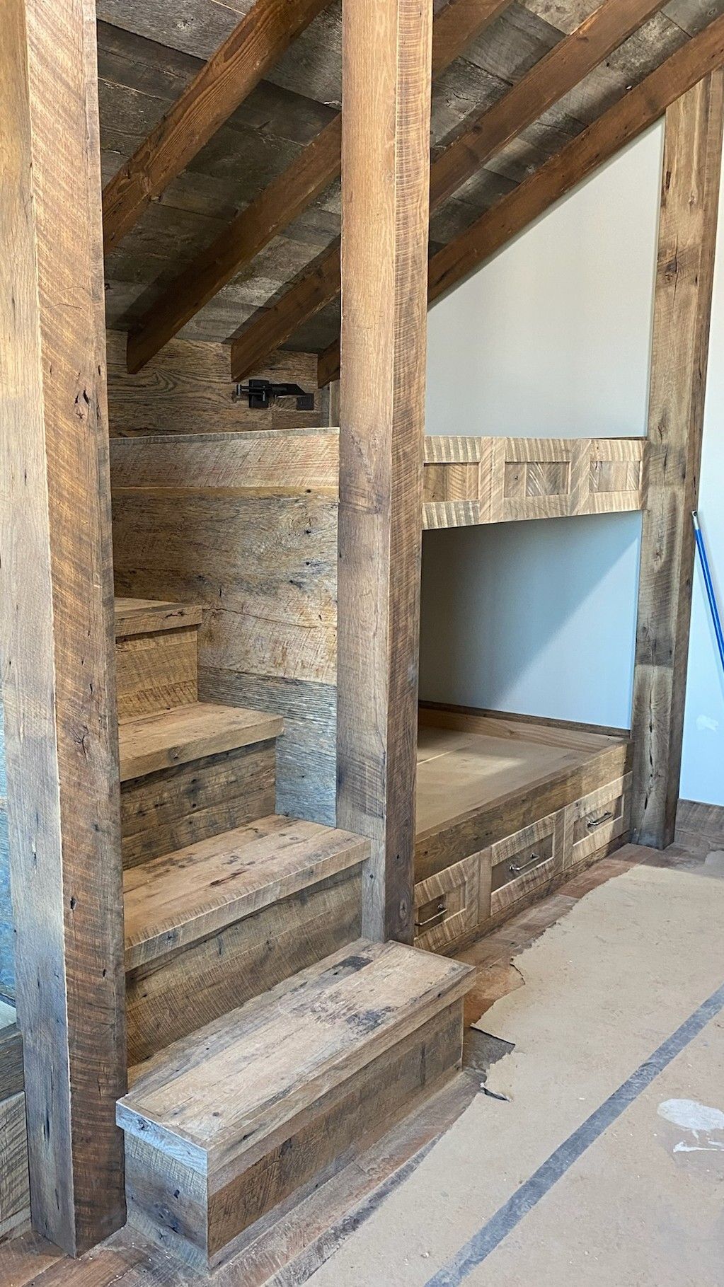 Rustic wooden bunk bed with stairs built into the wall.