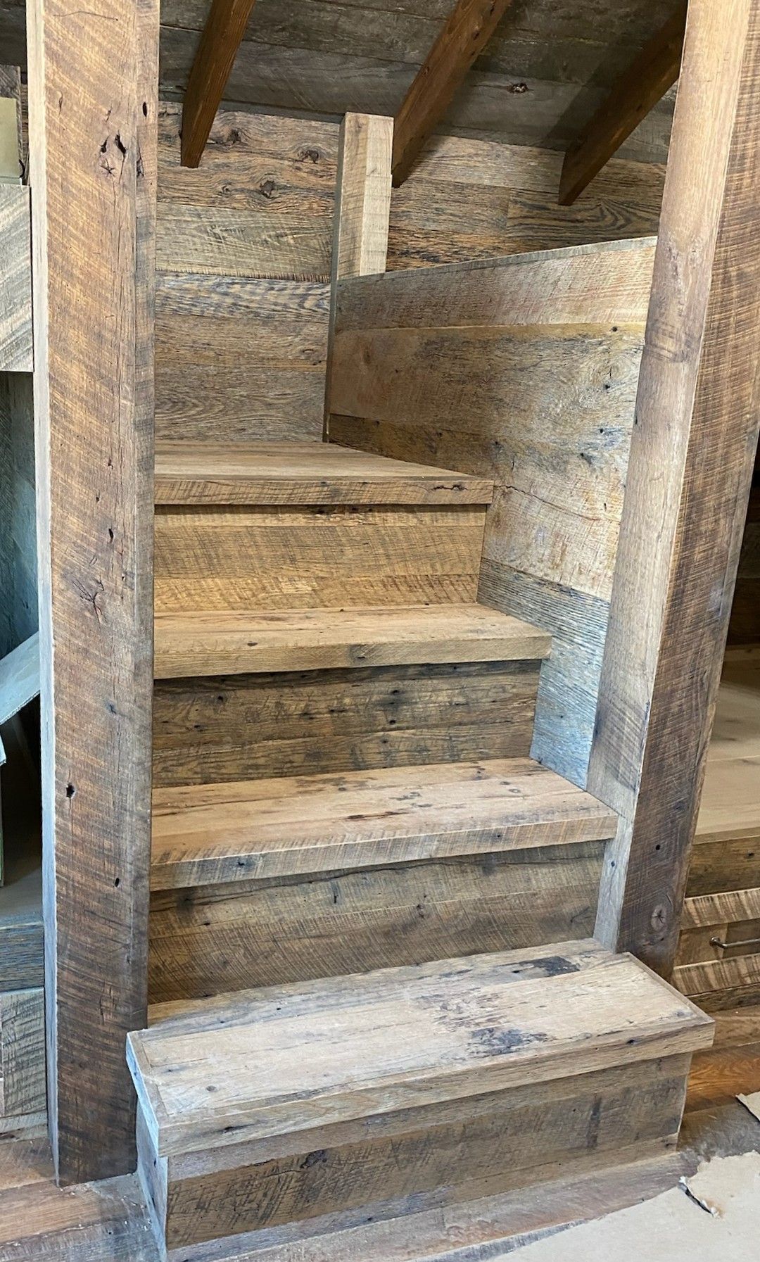 Wooden, rustic staircase ascending. Brown wood, rough texture, exposed beams.