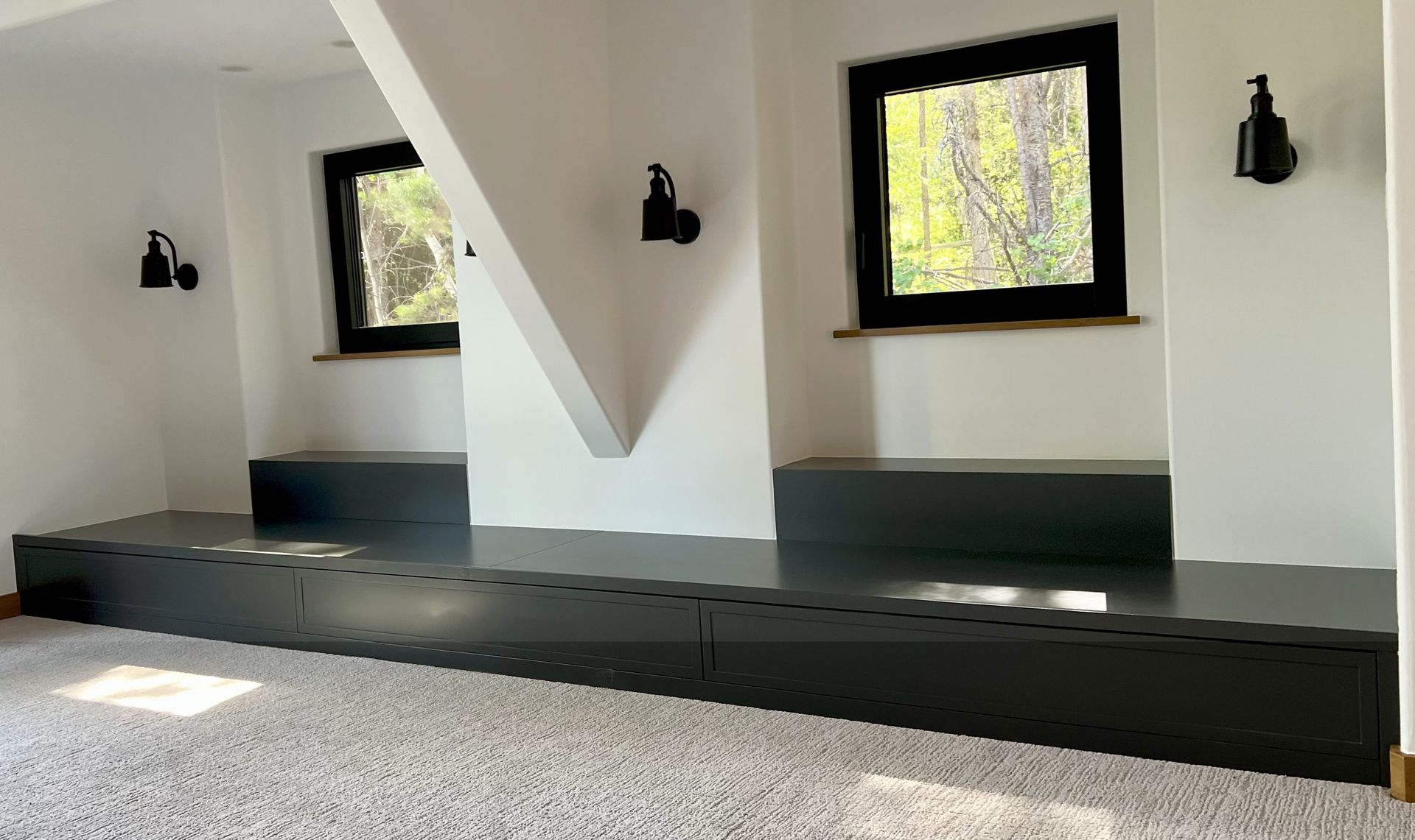 Gray elevated platform with windows, sconces, and a white wall.