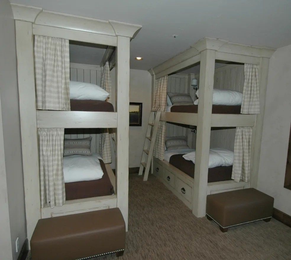 Two sets of bunk beds in a room, each with two beds, curtains, and a bench.