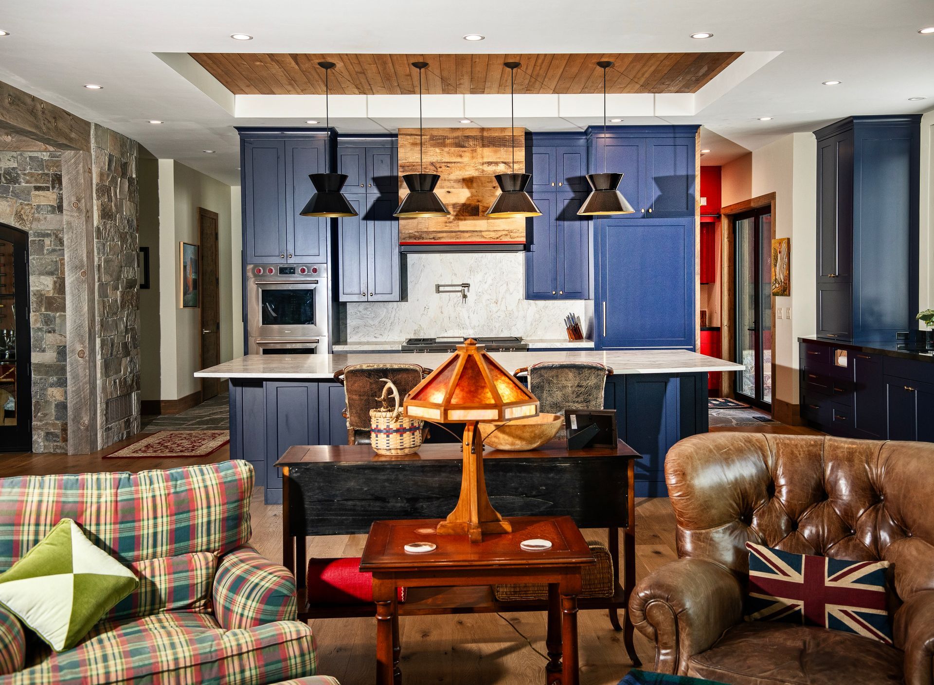 Kitchen with blue cabinets, wooden ceiling, and a cozy living area with leather chairs.