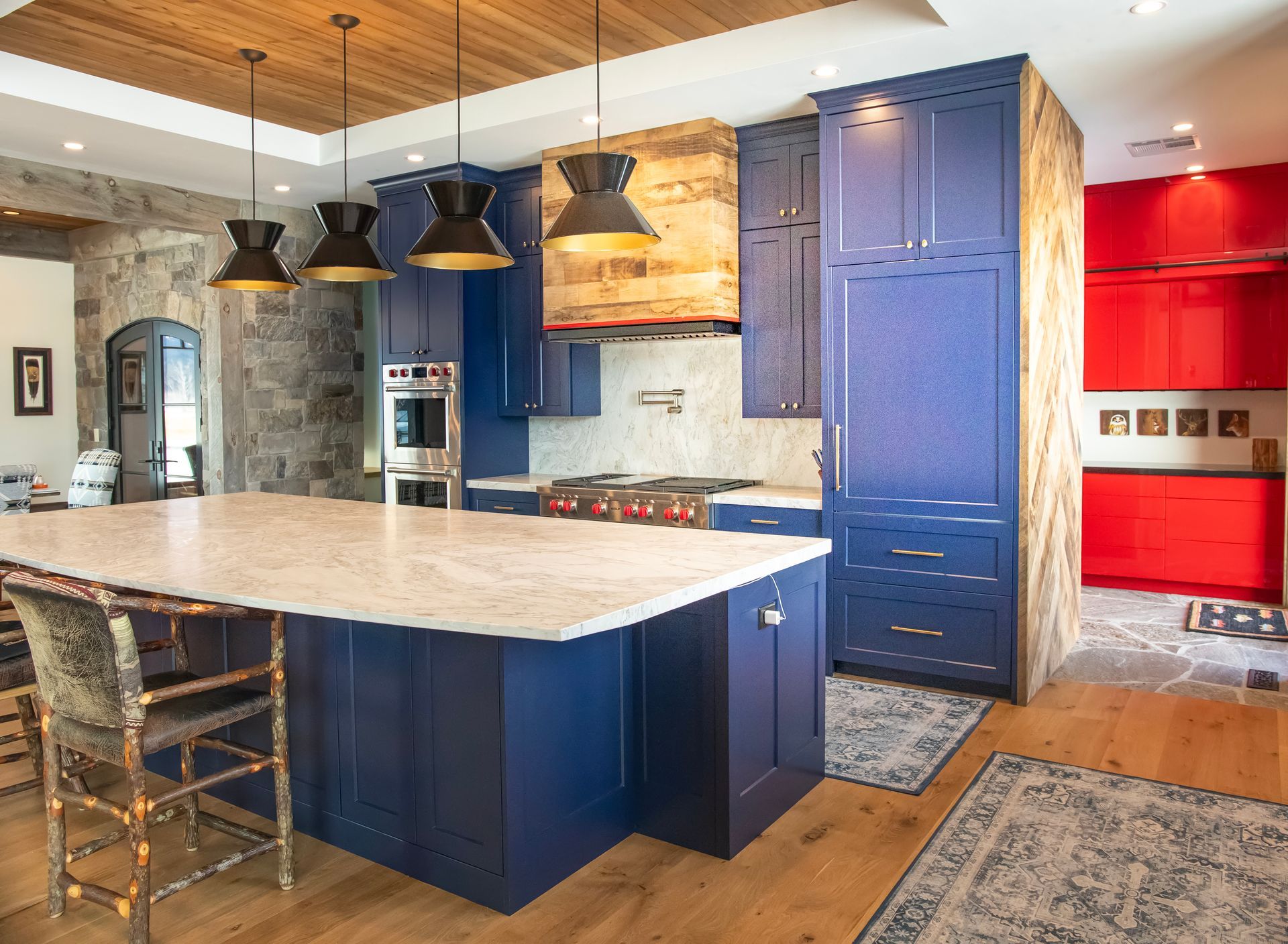 Modern kitchen with blue cabinets, white countertop island, and red accent cabinets.