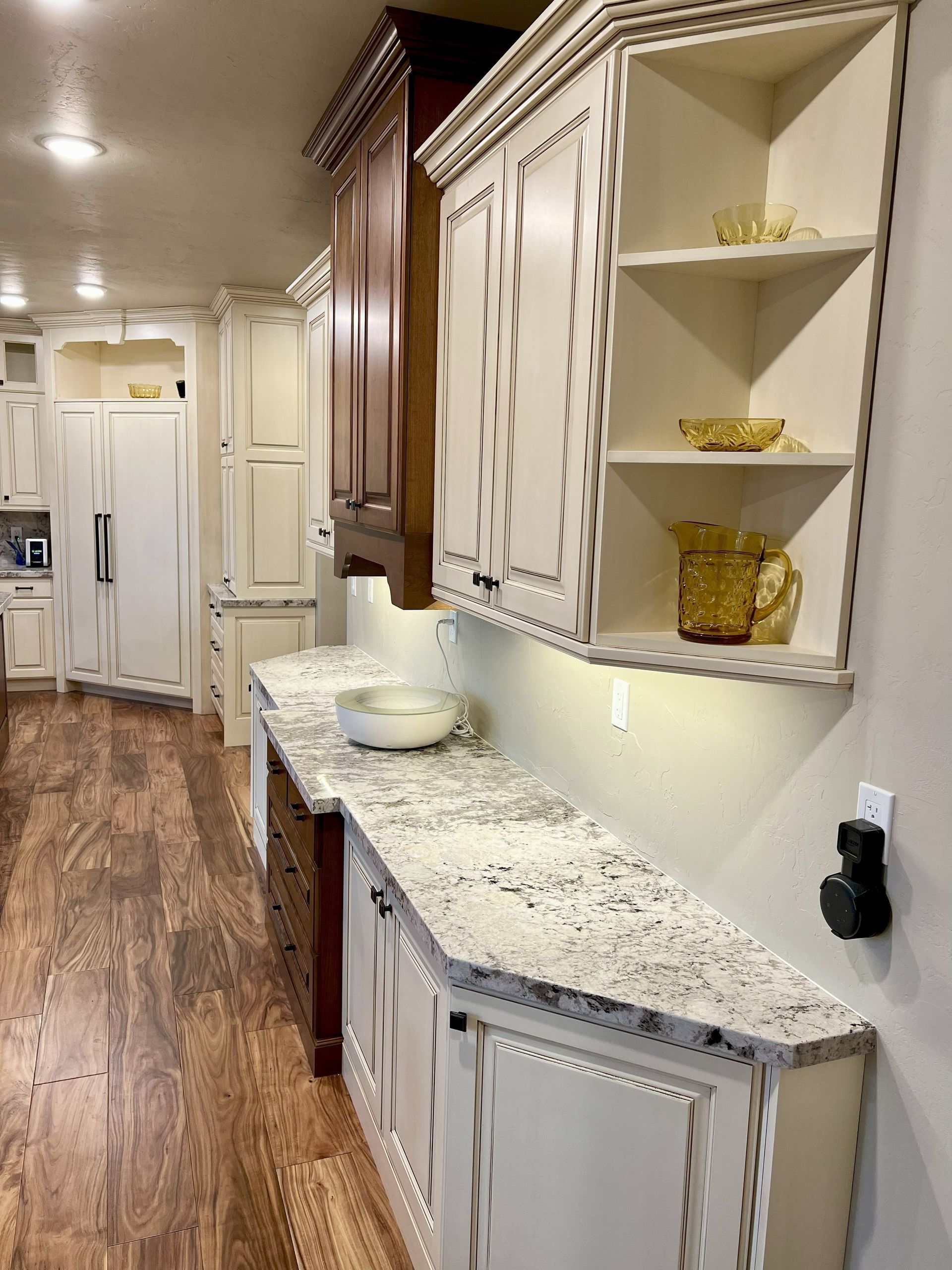 Kitchen with white cabinets, granite countertops, and a decorative shelf holding glassware.