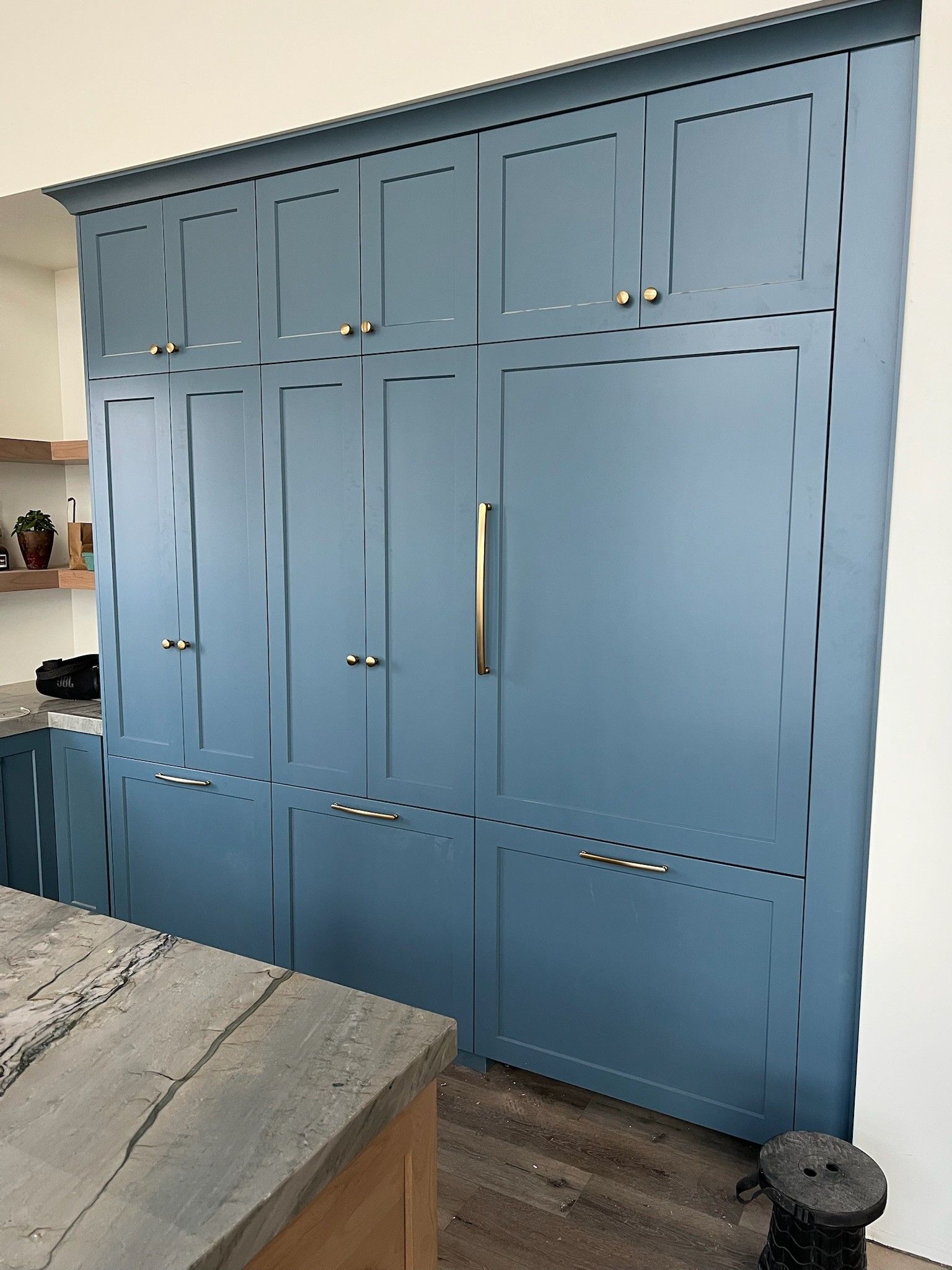 Blue built-in refrigerator and cabinet, with gold and silver handles, in a kitchen.