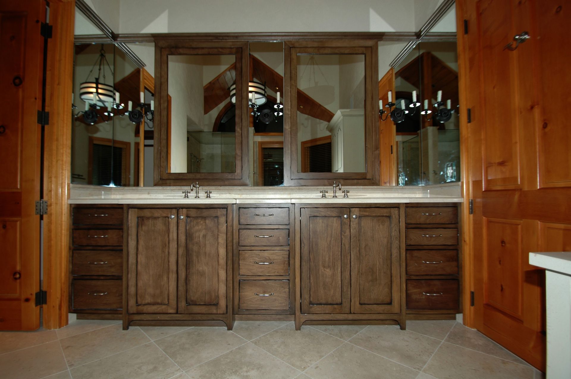 Bathroom with dark wood vanity, three mirrors, and beige tiled floor.