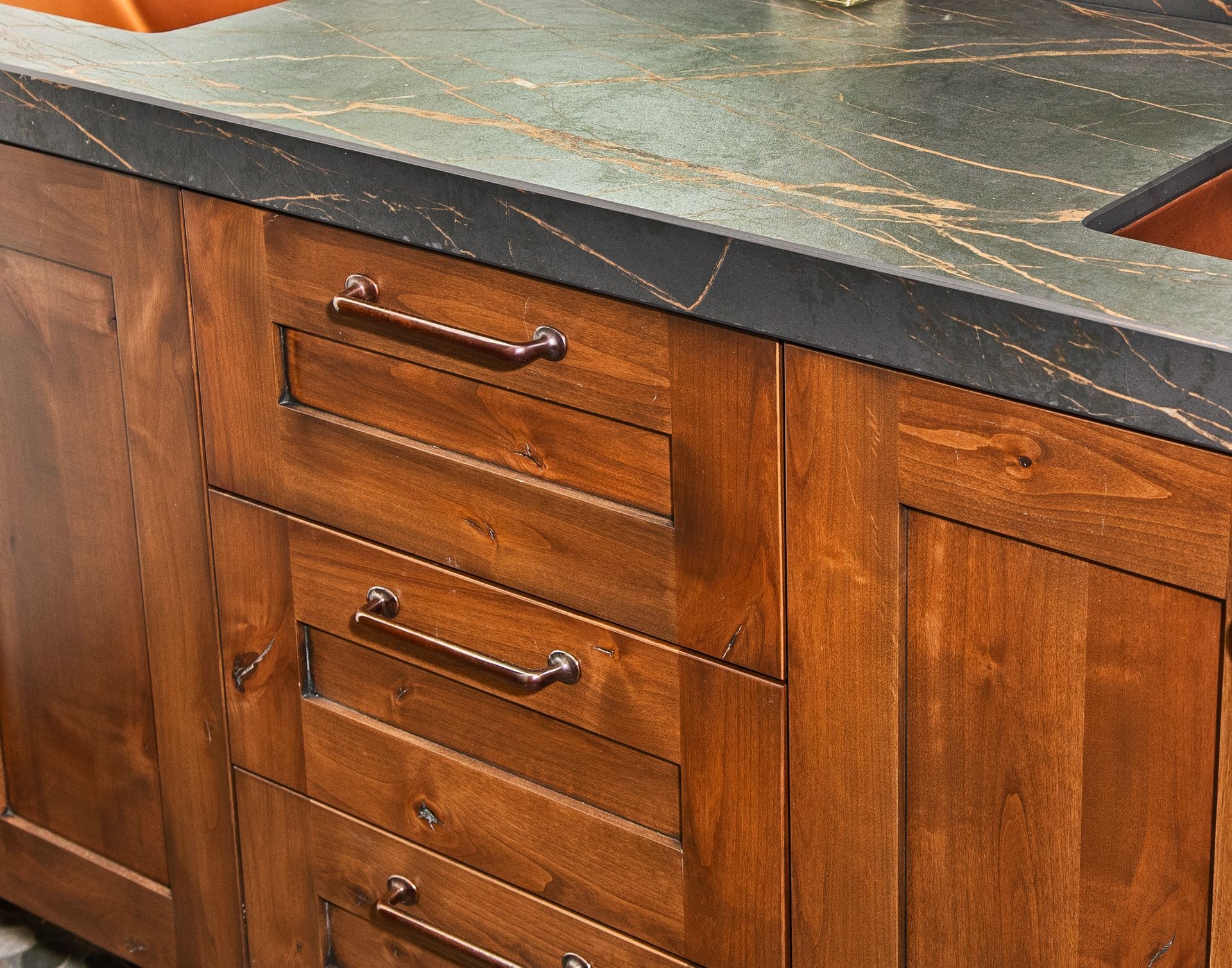 Wooden bathroom cabinet with drawers and dark countertop.