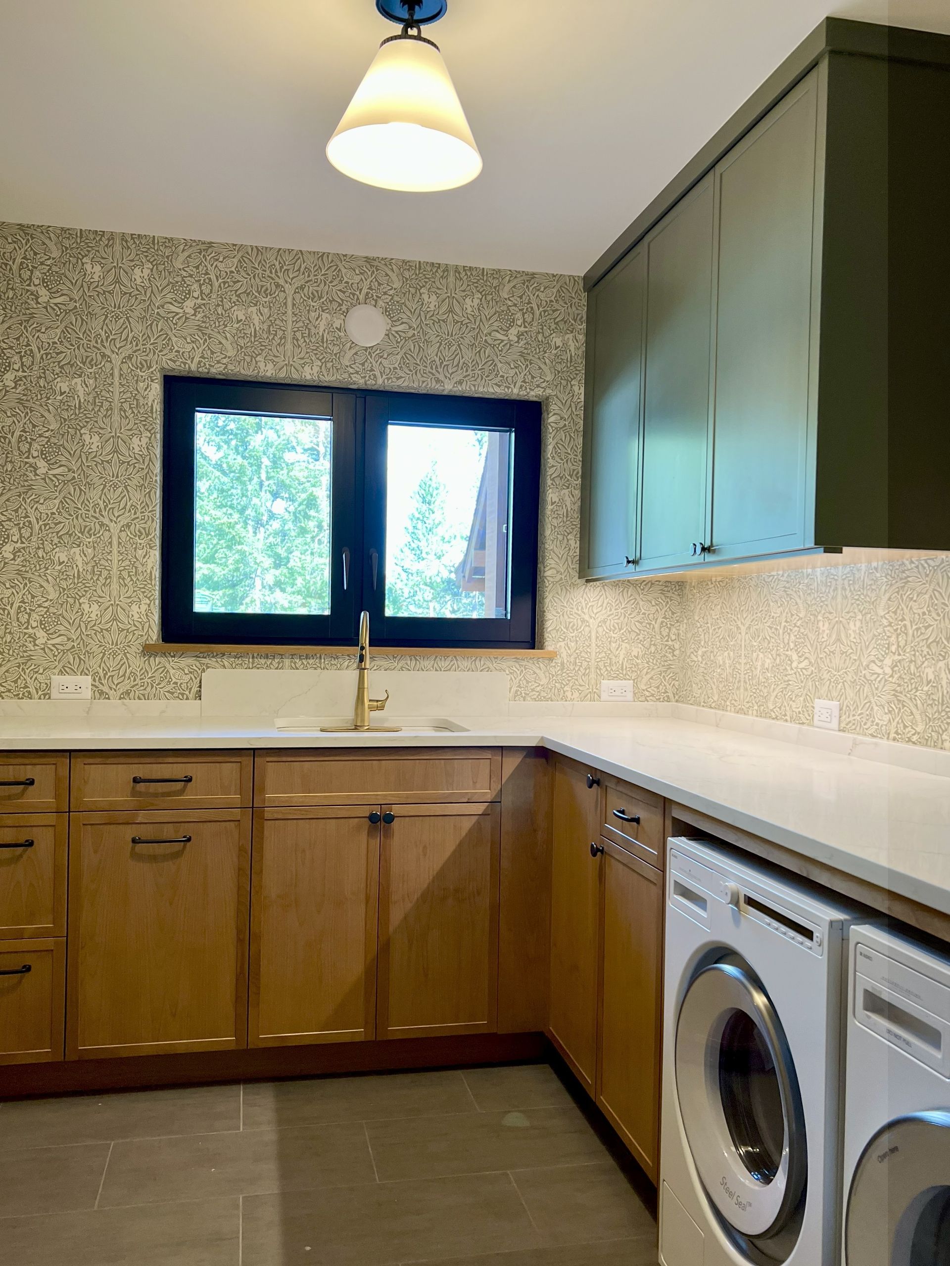 Laundry room with light wood cabinets, white countertop, and a green accent cabinet.