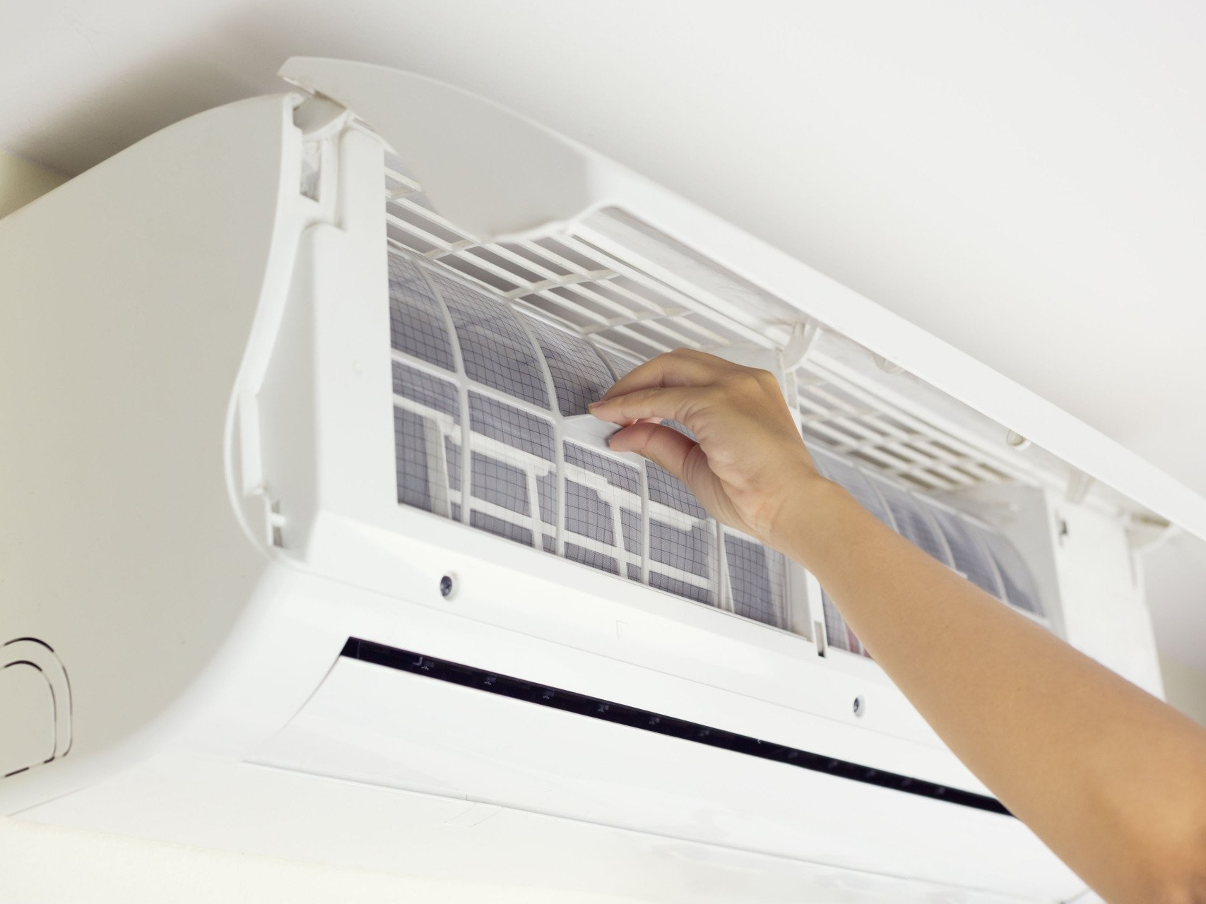 A person is cleaning the filter of an air conditioner.