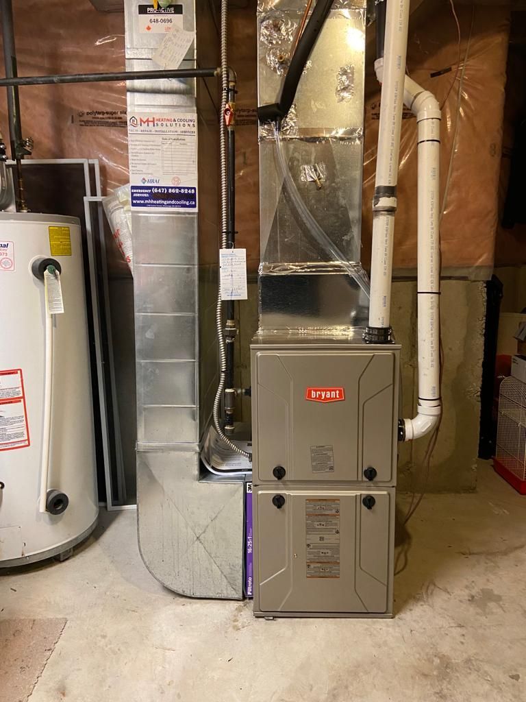 A furnace is sitting in a basement next to a water heater.