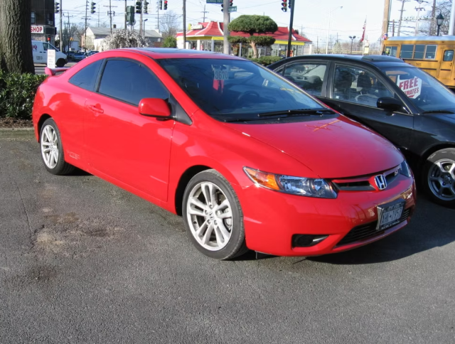 Red Honda Civic coupe parked on asphalt.