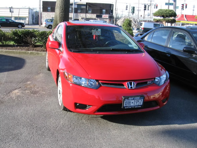 Red Honda Civic car parked outdoors with a New York license plate.