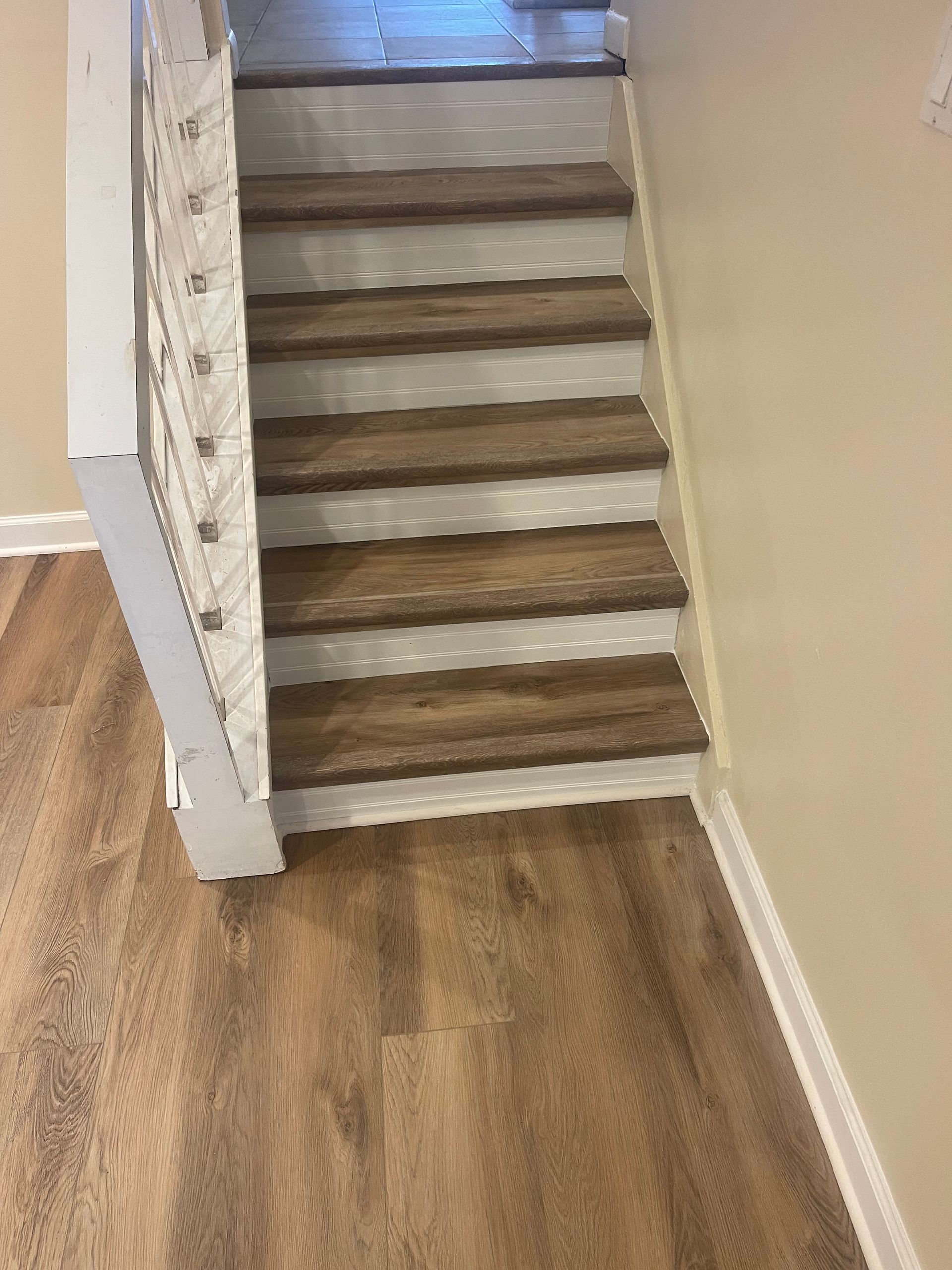 Staircase with wooden steps and white risers, leading upwards from a wood-look floor.