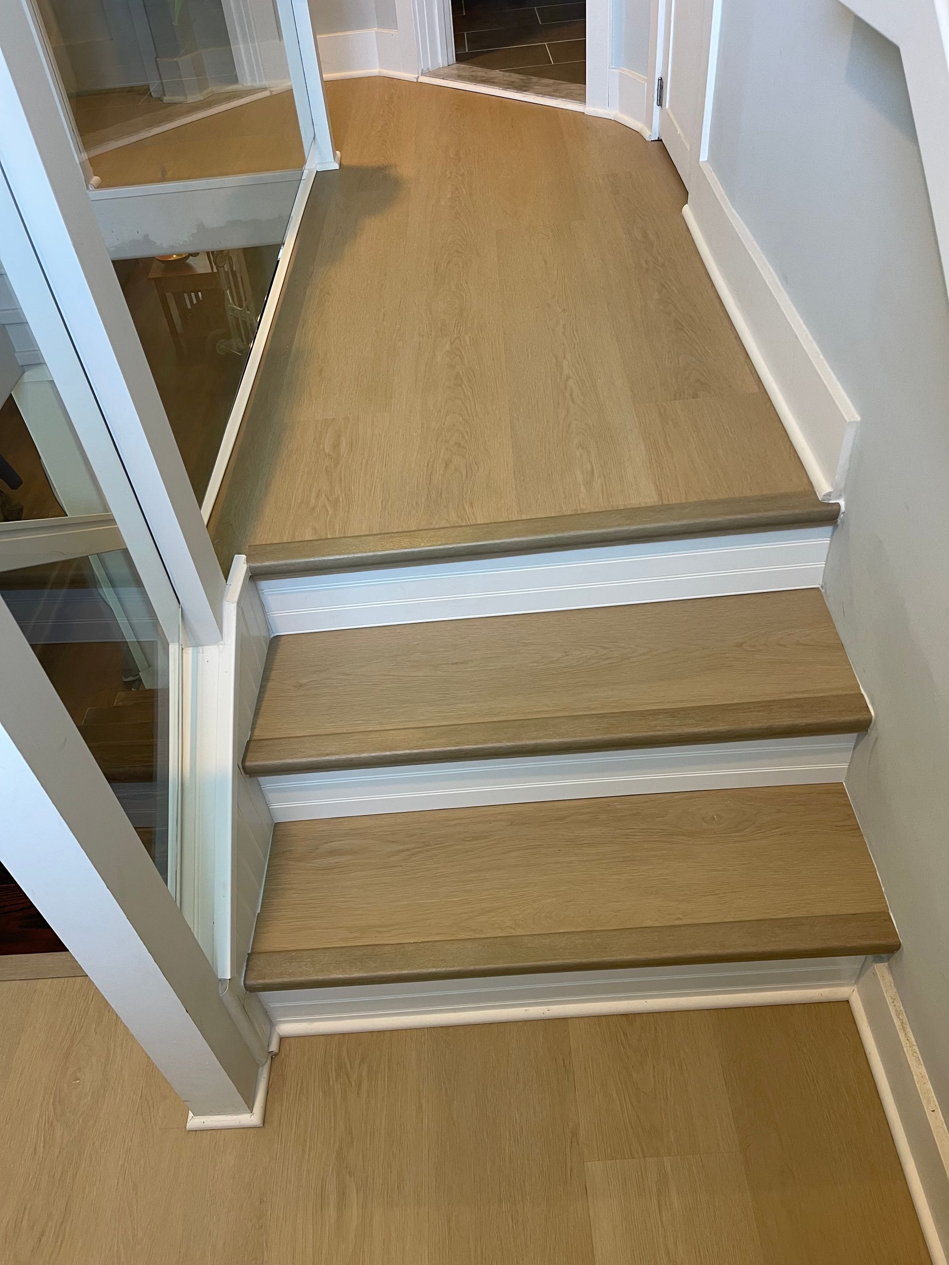 Wooden staircase with three steps, white trim, and a handrail.