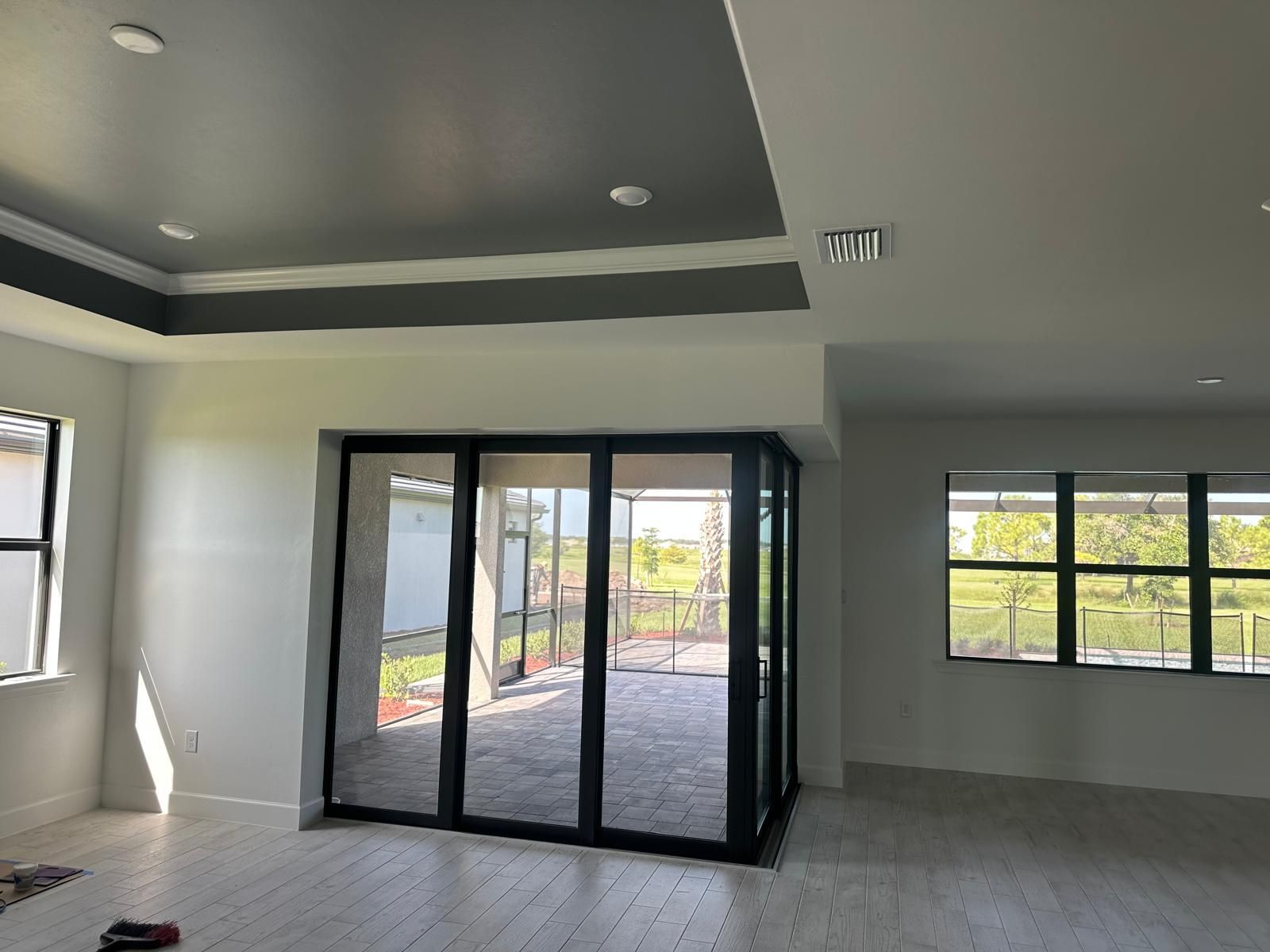 Interior view of a modern living space with a folding glass door to a patio, white walls, and a gray ceiling.