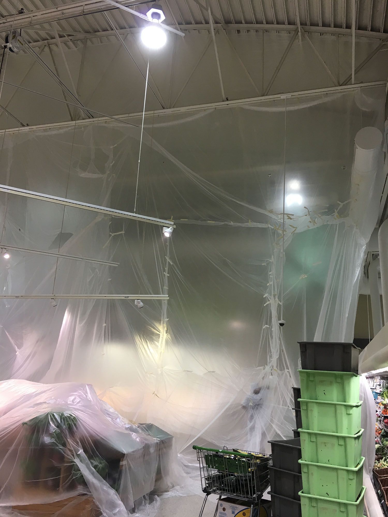 A room with a lot of plastic covering it and a light hanging from the ceiling.
